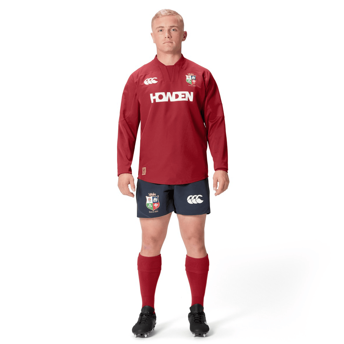 A person is wearing the British &amp; Irish Lions 25 Drill Top by Canterbury, paired with navy shorts, red socks, and black boots, and is facing forward.