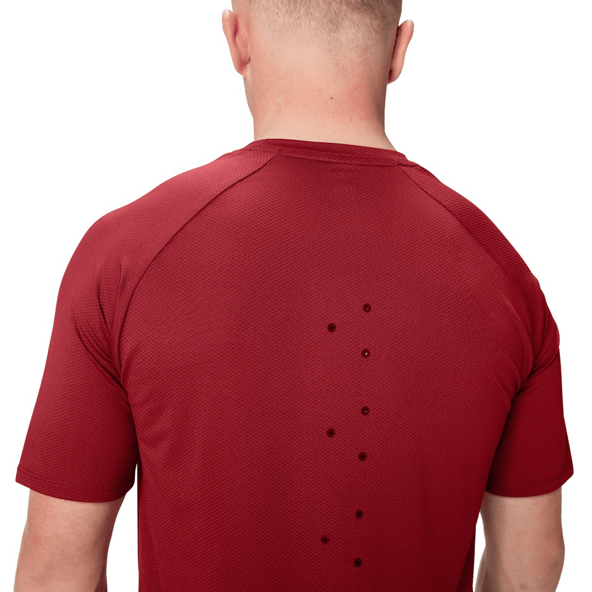 A person wearing a red British &amp; Irish Lions 25 Everest Tee by Canterbury, featuring small ventilation holes on the back.