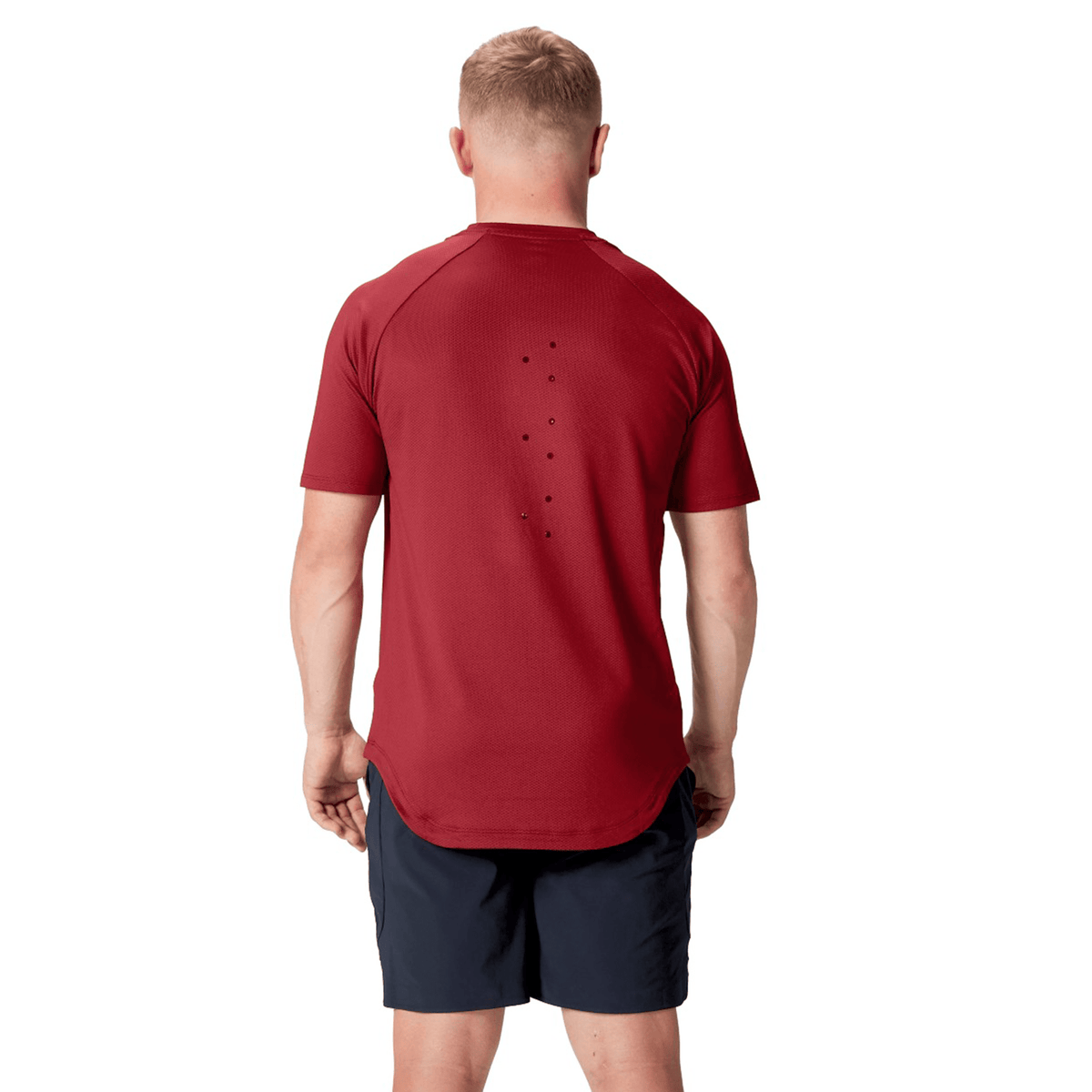 A person is shown from the back wearing the vibrant red short-sleeves of a British &amp; Irish Lions 25 Everest Tee by Canterbury, paired with navy shorts.