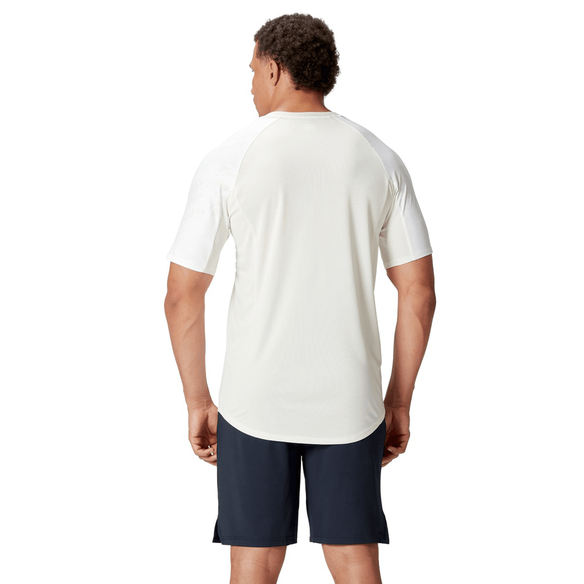 A person wearing the British &amp; Irish Lions 25 Superlight Training Tee by Canterbury in white, along with black shorts, is standing and facing away, embodying the spirit of the British &amp; Irish Lions.