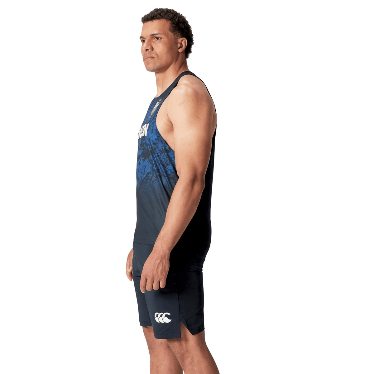 A man wearing a British &amp; Irish Lions 25 Poly Singlet by Canterbury and shorts stands facing left against a white background.