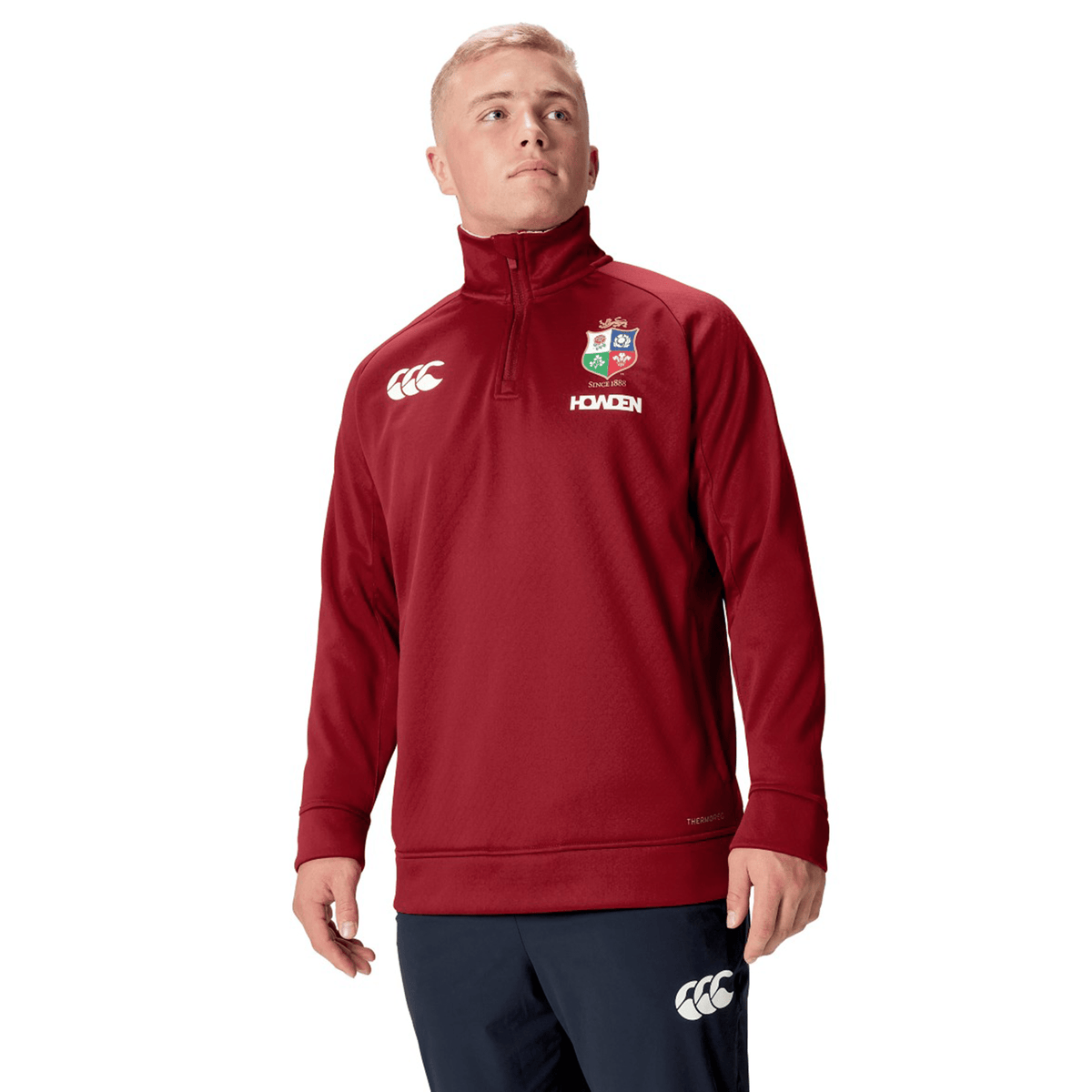 A person wearing the British &amp; Irish Lions 2025 1/4 Zip Fleece by Canterbury stands against a white background, embodying the iconic style of the British &amp; Irish Lions.