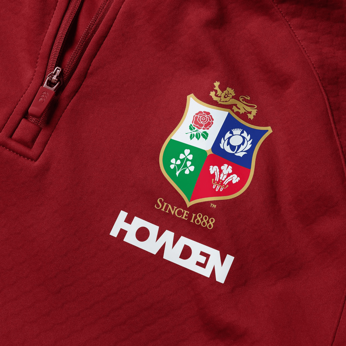 The British &amp; Irish Lions 2025 quarter-zip fleece by Canterbury is a red top showcasing the team&#39;s crest with &quot;Since 1888&quot; and &quot;Howden&quot; gracefully printed beneath the logo.