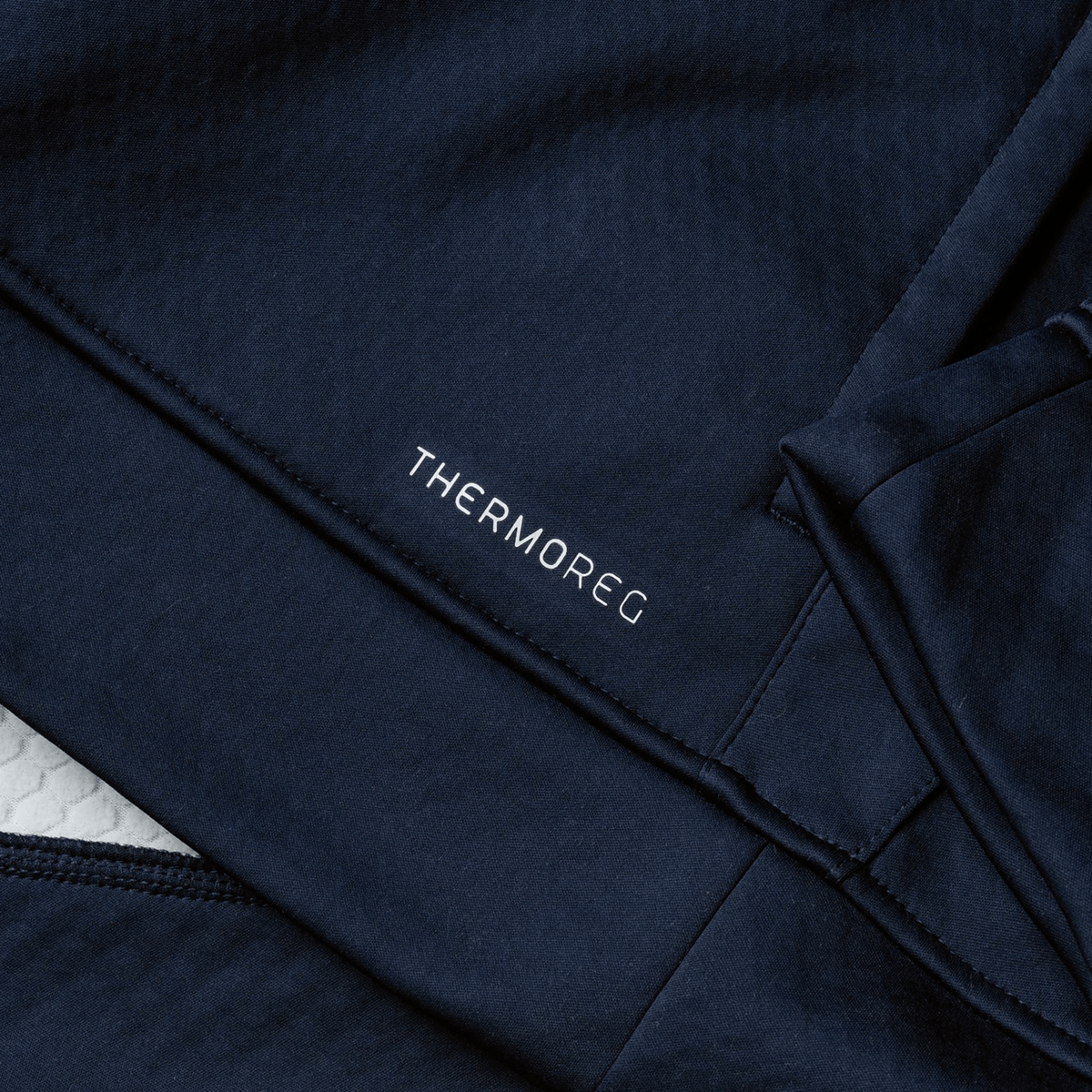 Close-up of dark blue fabric showcasing the word &quot;THERMOREG&quot; in white, echoing Canterbury&#39;s high-performance aesthetics, ideal for the British &amp; Irish Lions 2025 1/4 Zip Fleece by Canterbury.