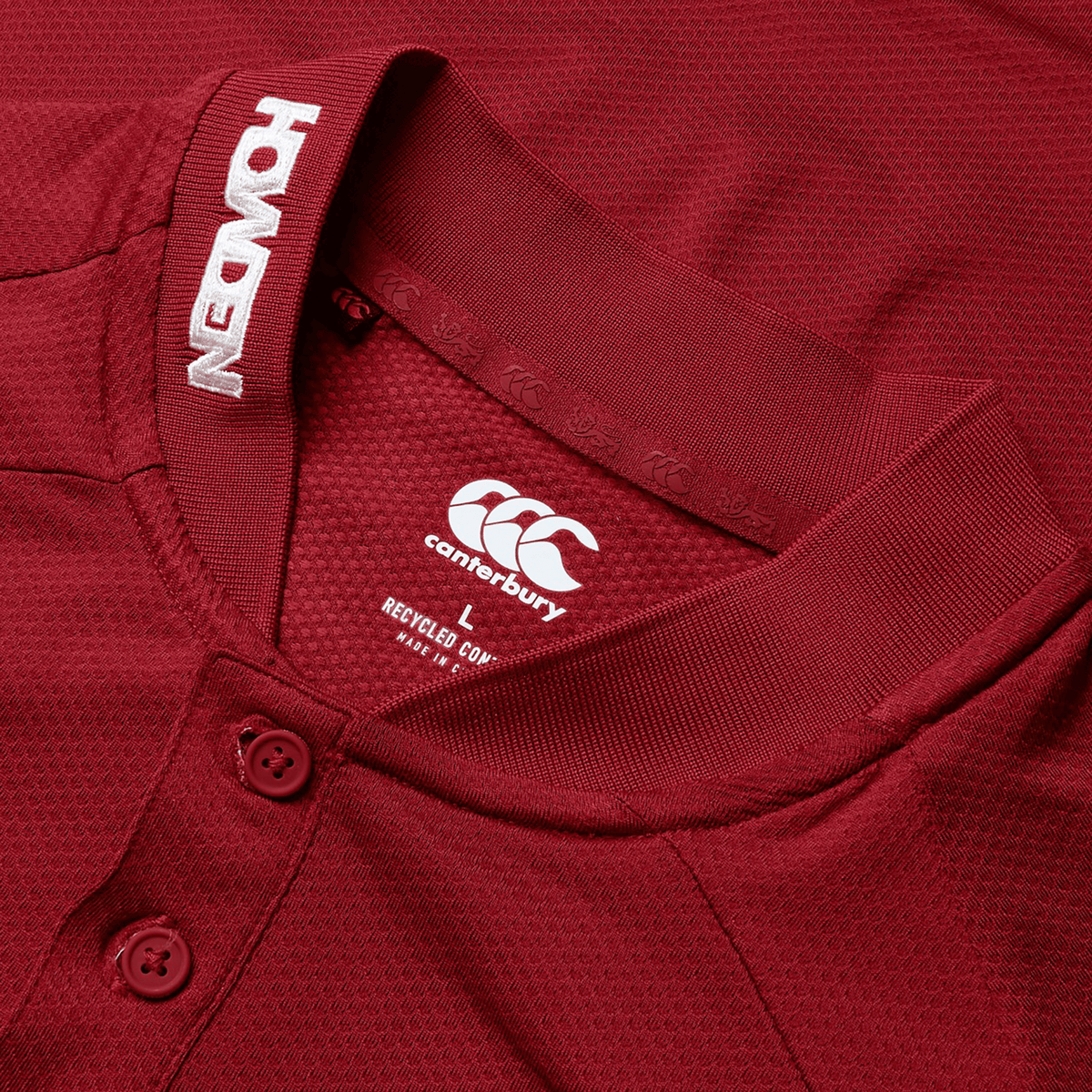 Close-up of a maroon British &amp; Irish Lions 25 Poly Polo by Canterbury featuring a polo-style collar with buttons. The jersey showcases the Canterbury logo along with the text "REUSED" and "NEW ORIGINS" on the inner collar.