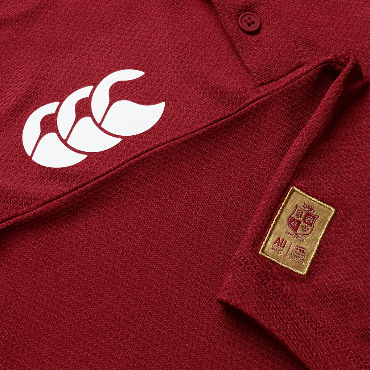 Close-up of a maroon British &amp; Irish Lions Poly Polo, made from breathable fabric, featuring a prominent white Canterbury logo and an AU patch with crest and text.