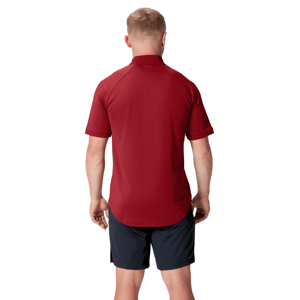 A man with his back to the camera wears the British &amp; Irish Lions 25 Poly Polo by Canterbury in red, designed for breathability, paired with black shorts against a pristine white background.