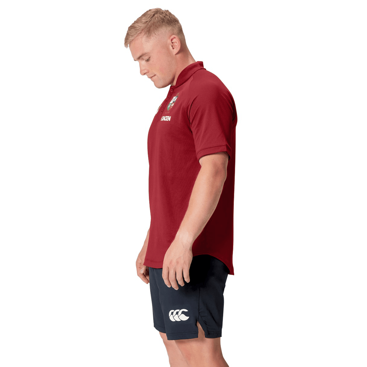 A man wearing the British &amp; Irish Lions 25 Poly Polo by Canterbury, made from breathable fabric, stands against a white background, looking down.