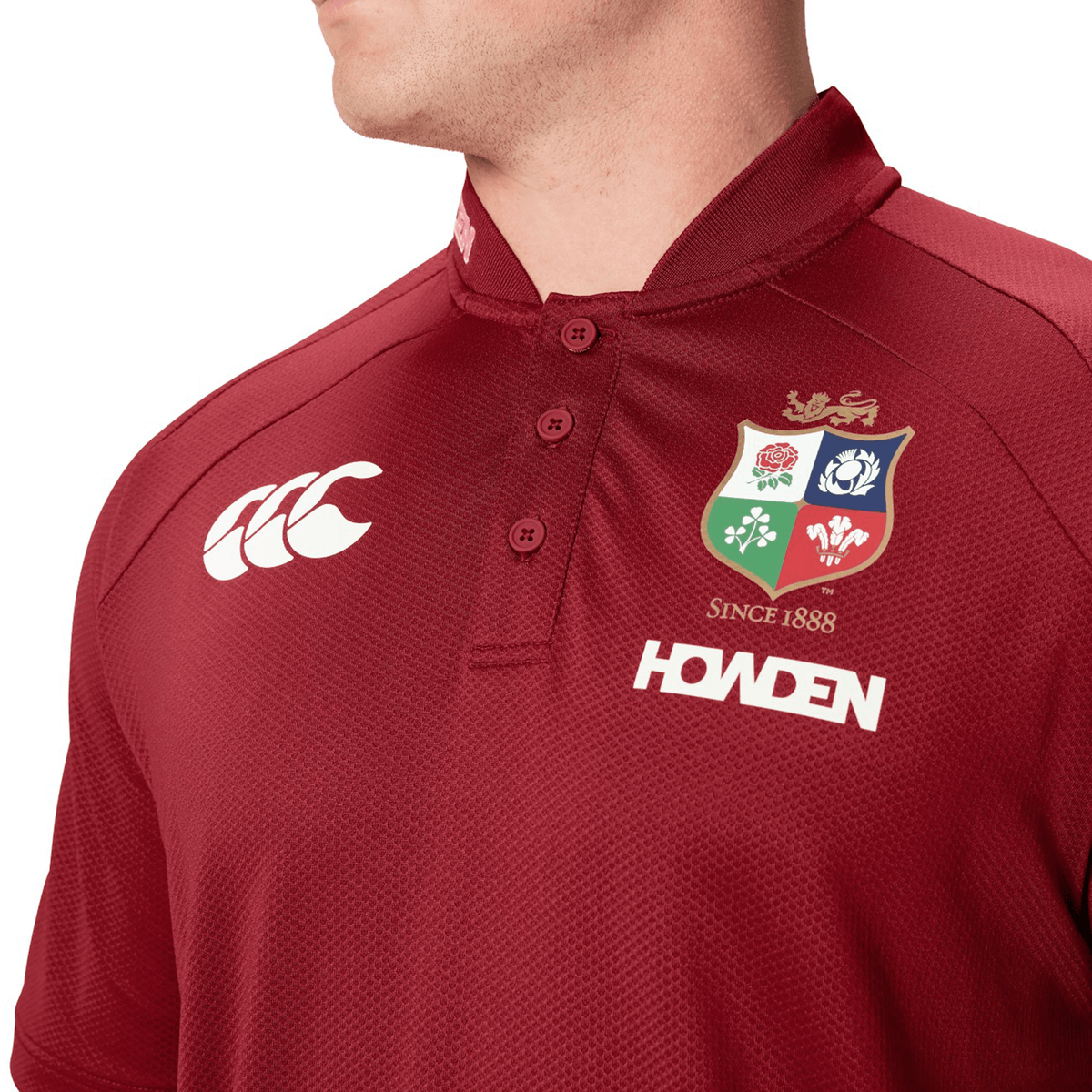 A person wearing a burgundy polo crafted from breathable fabric, showcasing Canterbury logos and adorned with a crest that reads "Since 1888" and "Howden.