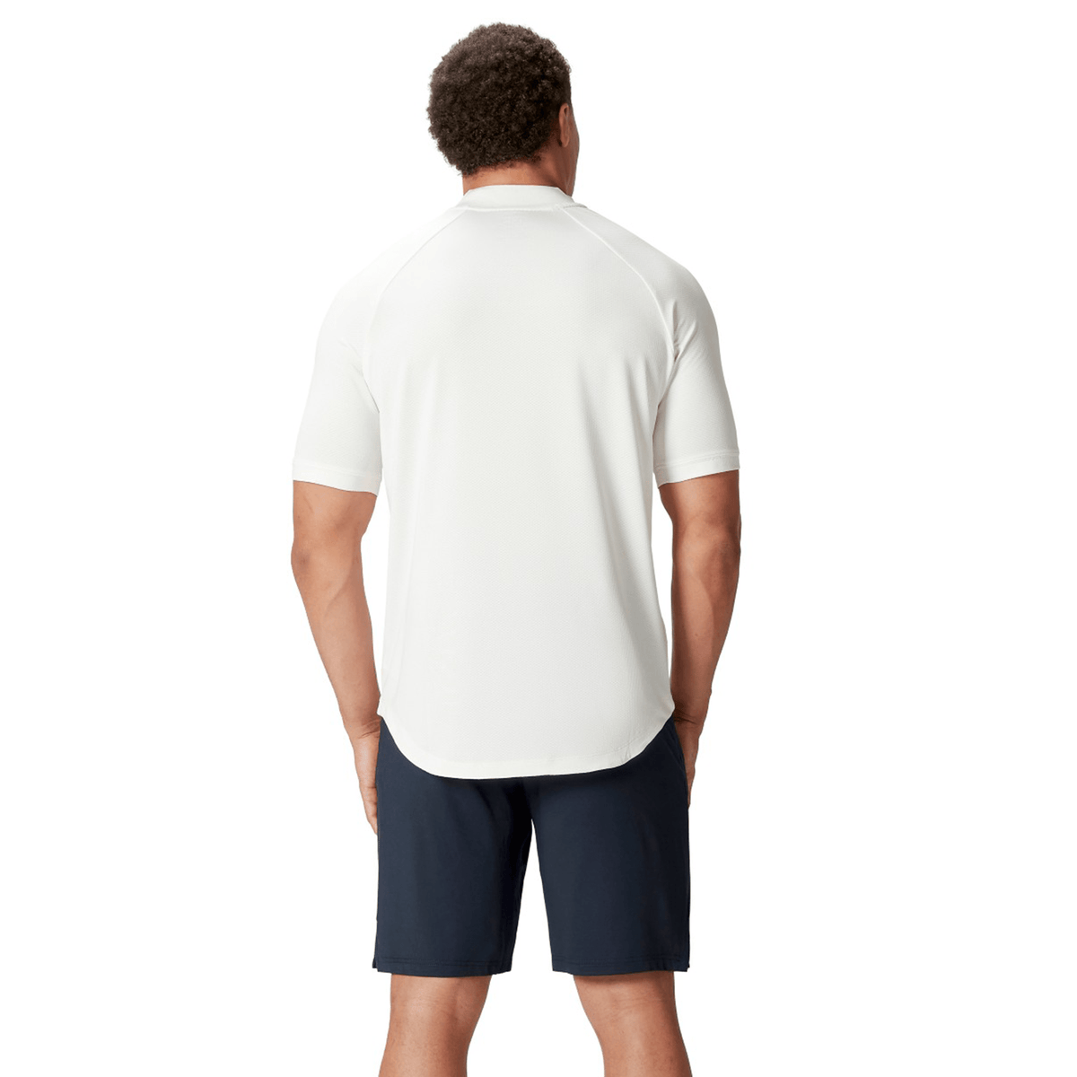 A man with short curly hair, wearing the British &amp; Irish Lions 25 Poly Polo by Canterbury and navy shorts, stands with his back turned, exuding the timeless charm of the British &amp; Irish Lions.