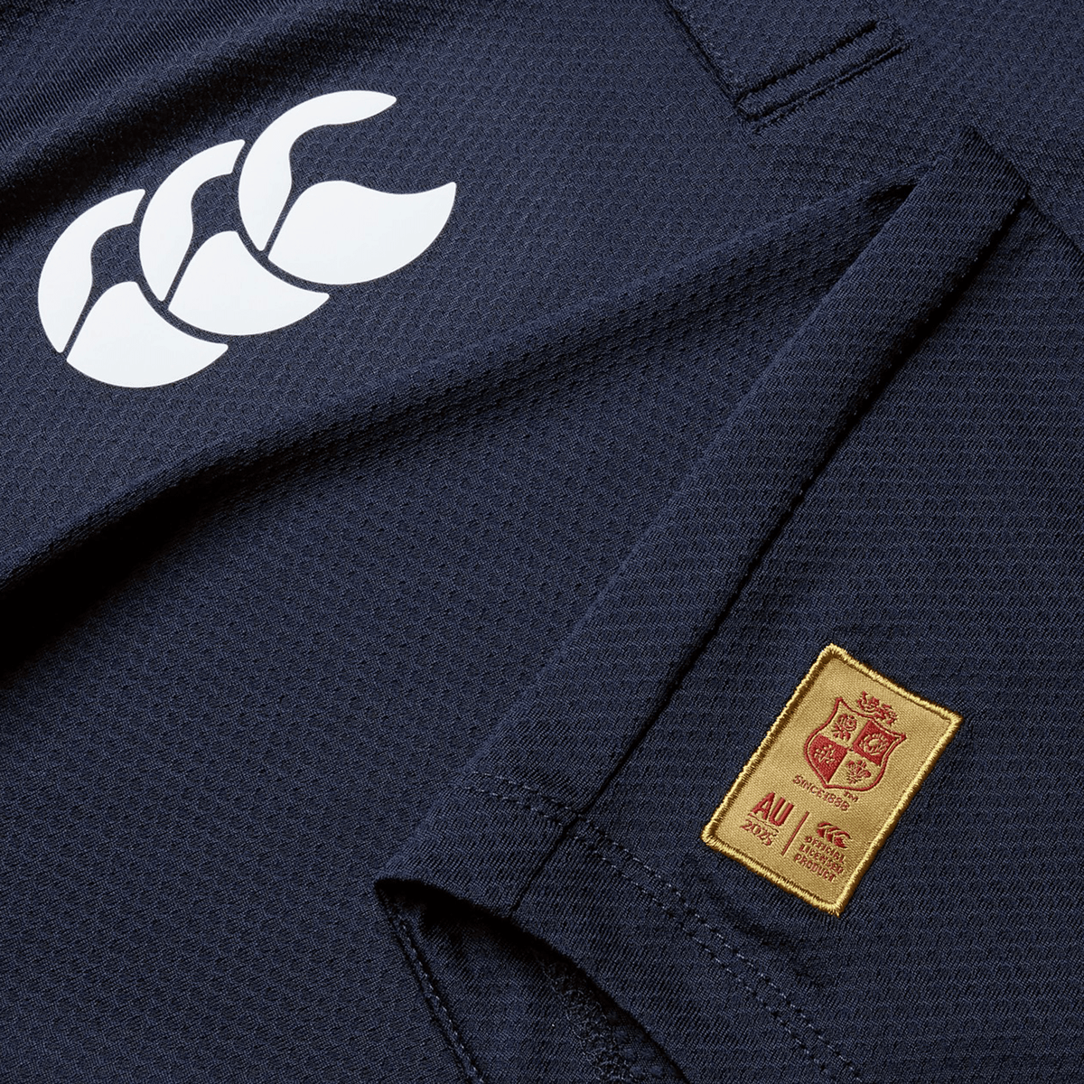 Close-up of the British &amp; Irish Lions 25 Poly Polo by Canterbury in navy blue, crafted from quick-drying fabric, showcasing a white logo on the right shoulder and an embroidered "AU" crest on the left side.