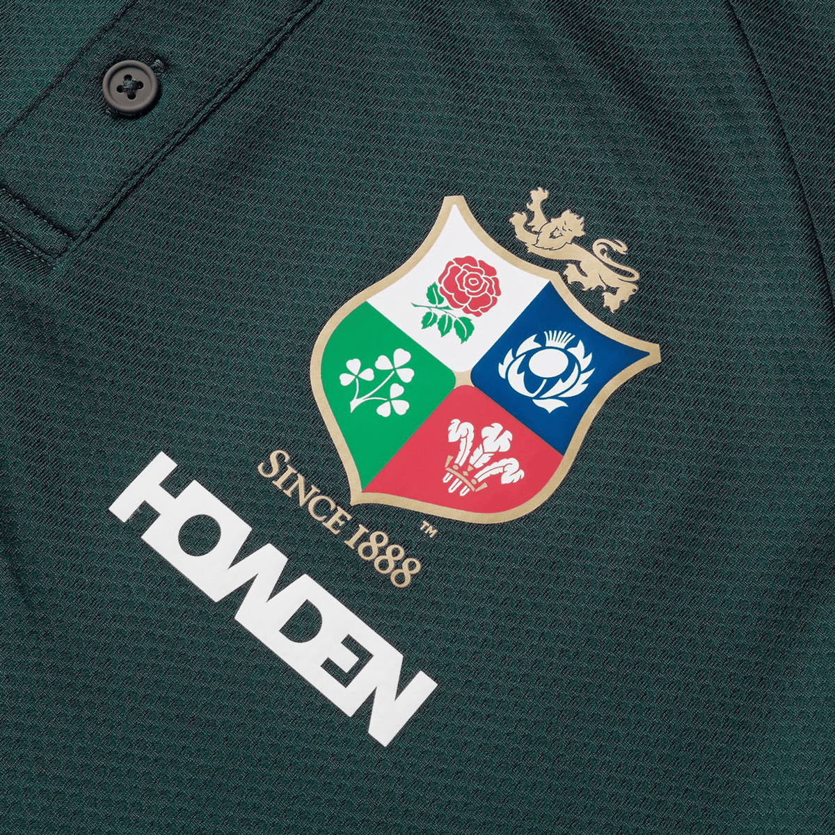 Close-up of the British &amp; Irish Lions 25 Poly Polo by Canterbury in dark green, made from breathable fabric, showcasing a multi-colored crest with a lion and various emblems above the words "Since 1888" and the Howden logo.
