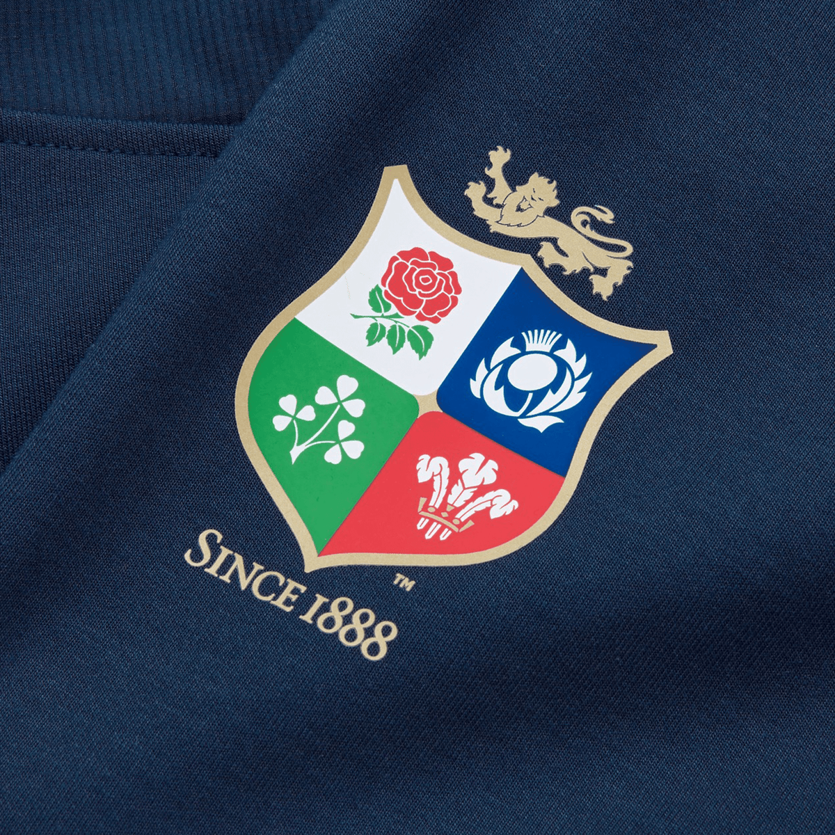 The British &amp; Irish Lions 25 Training Pants by Canterbury feature a crest displaying a red rose, thistle, shamrock, and red dragon with the text "Since 1888," all set against rich dark blue fabric.