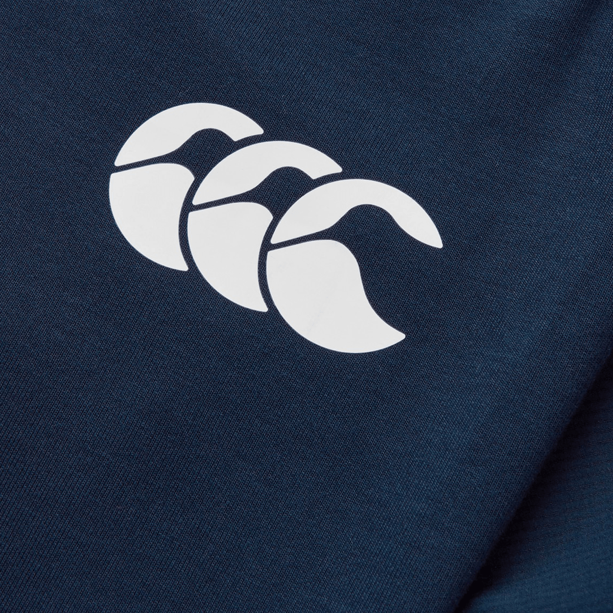 Close-up of a navy blue fabric from the British &amp; Irish Lions 25 Training Pants by Canterbury, showcasing a white logo with three stylized overlapping shapes that resemble waves.