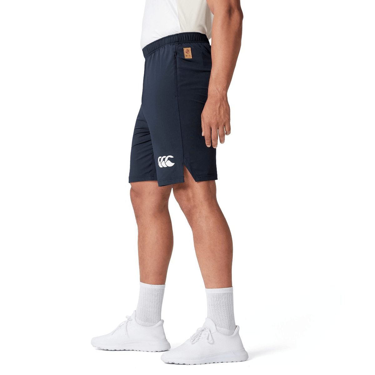 Person wearing the British &amp; Irish Lions 2025 Training Shorts by Canterbury in navy and white shoes, standing sideways.