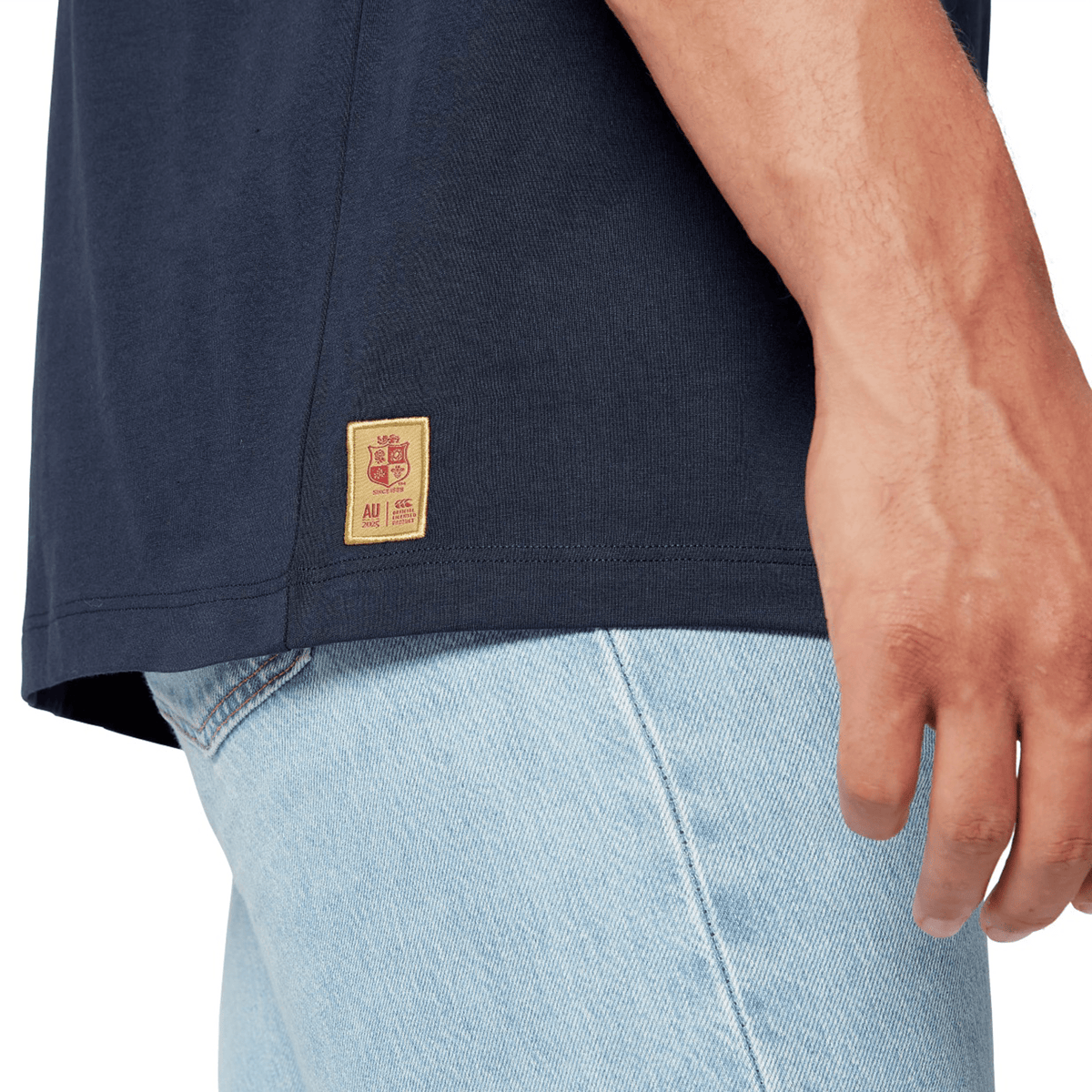 A close-up of a rugby supporter wearing the British &amp; Irish Lions 2025 Cotton Jersey Tee by Canterbury paired with light blue jeans, embodying the spirit of the team.
