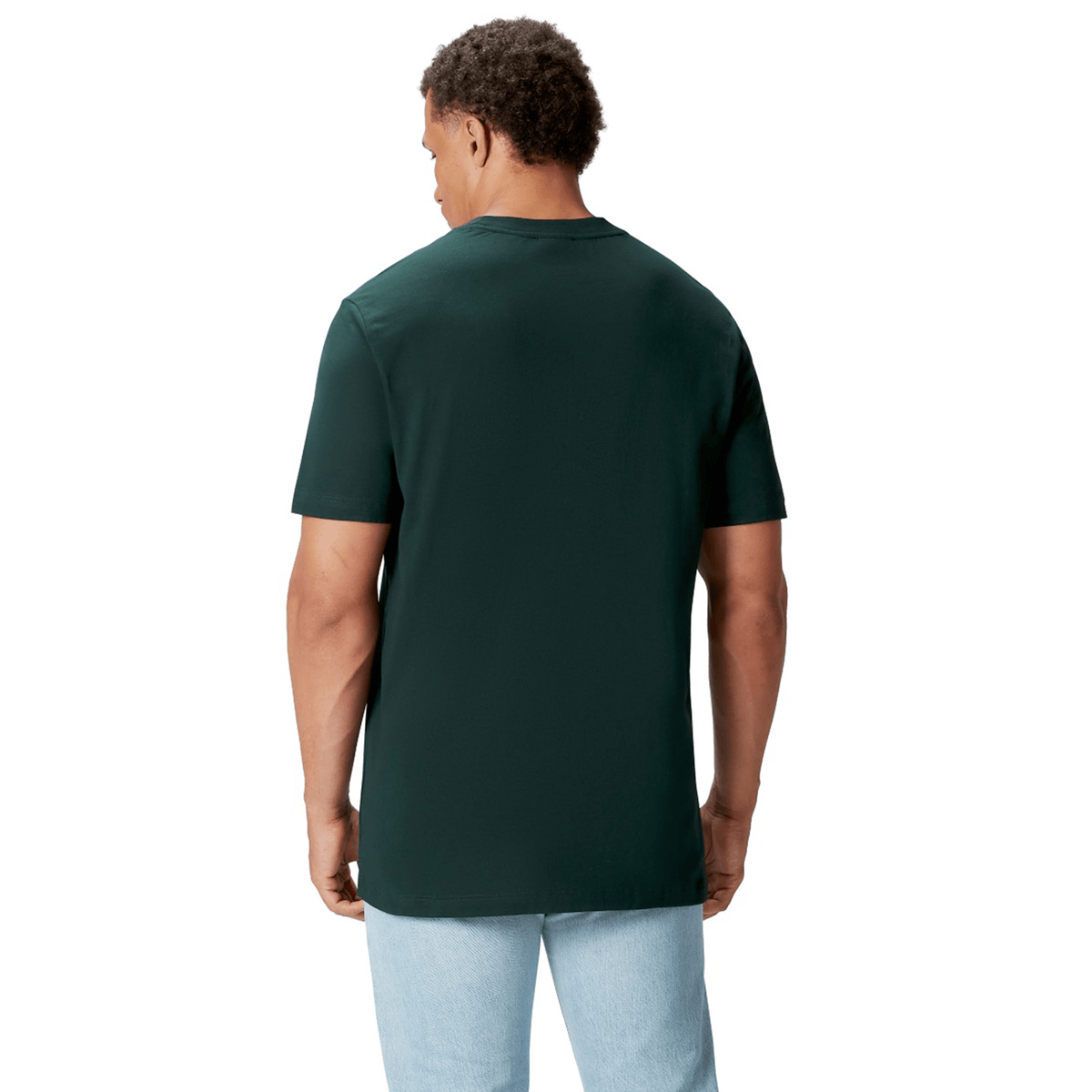 A rugby supporter stands with their back to the camera, wearing a British &amp; Irish Lions 2025 Cotton Jersey Tee by Canterbury in dark green and light blue jeans, set against a plain white background.