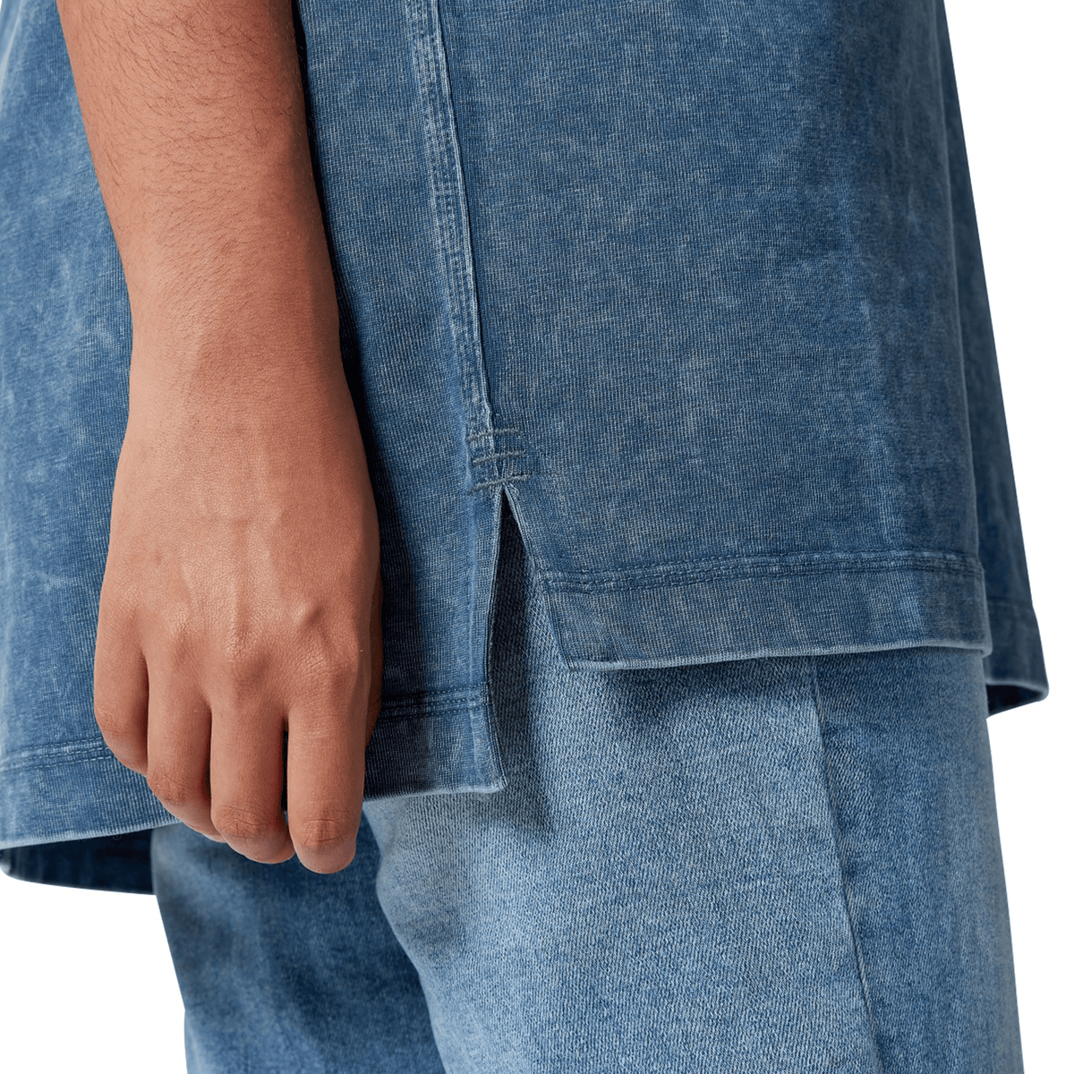 Close-up of a person wearing a faded blue ensemble, embodying Canterbury&#39;s signature style, with their hand resting by their side.