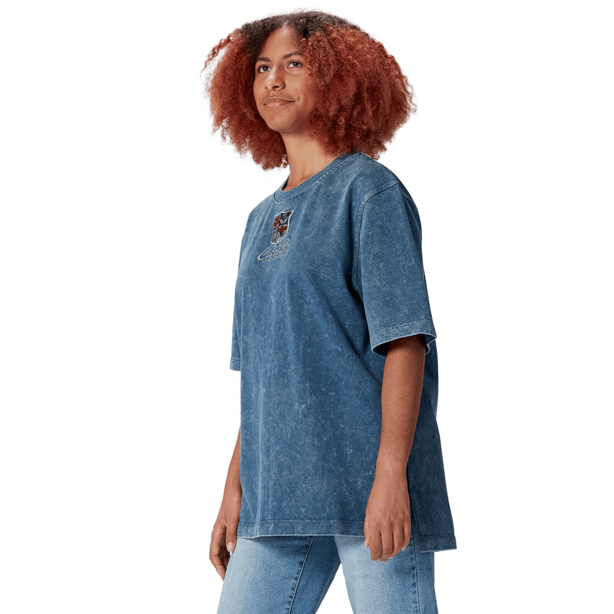 A person wearing a loose-fitting blue British &amp; Irish Lions 25 Heritage Tee by Canterbury and jeans, crafted from organic cotton, stands while looking slightly upward.