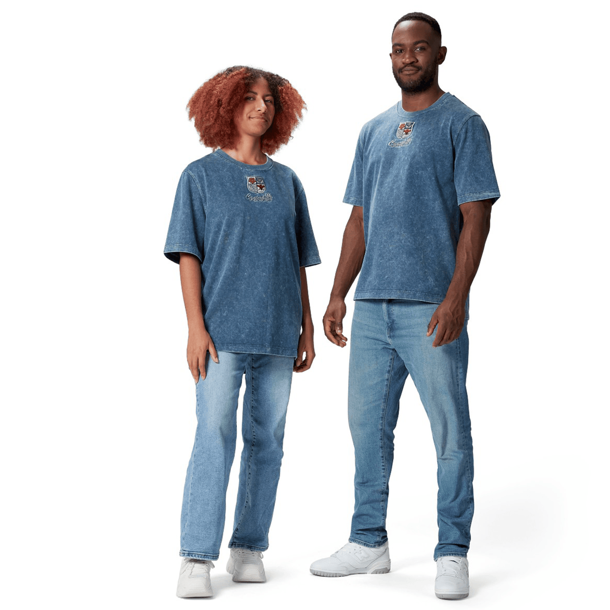 Two people stand side by side against a plain white background, wearing matching blue denim attire that includes jeans and the British &amp; Irish Lions 25 Heritage Tee by Canterbury.
