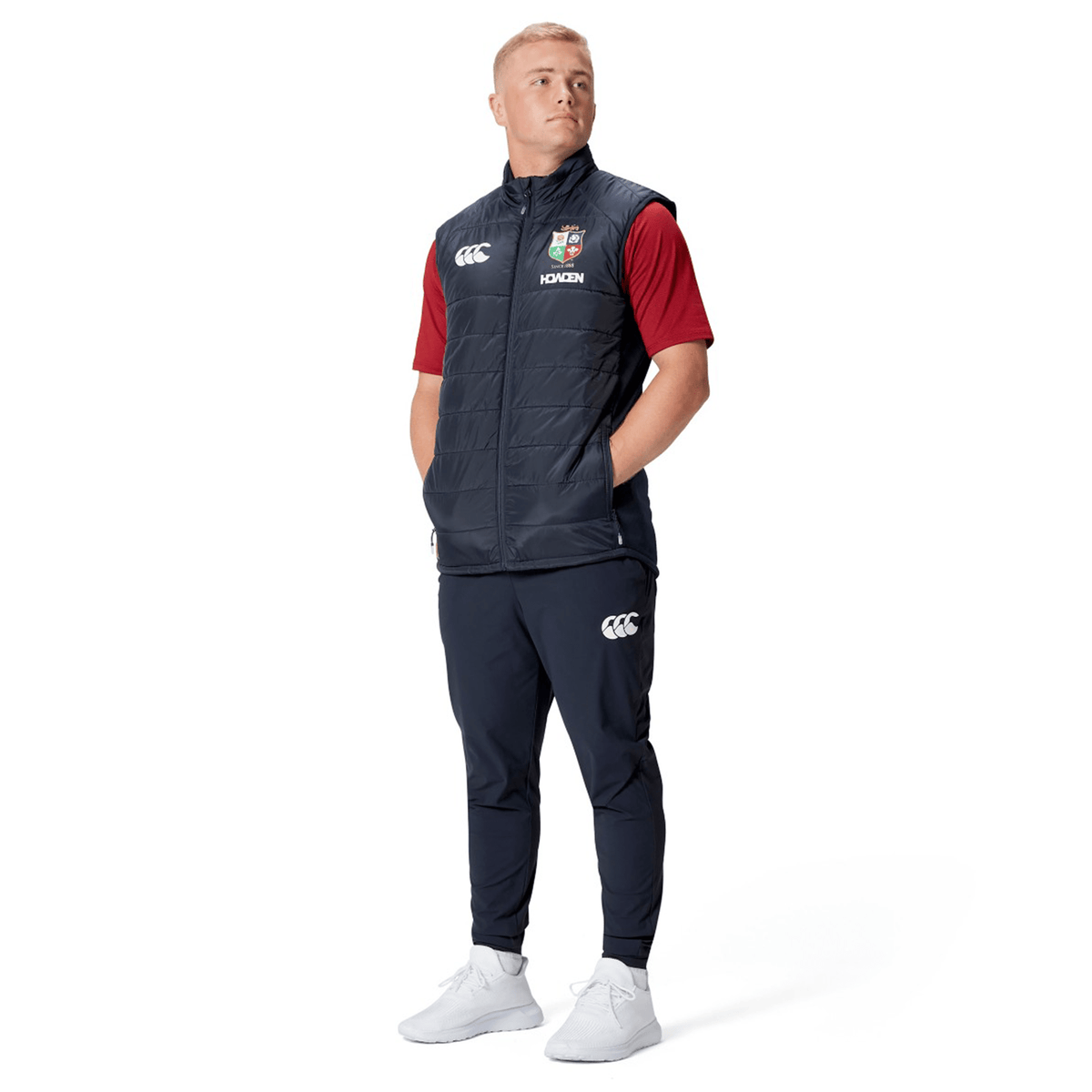 A person wearing the British &amp; Irish Lions 2025 Microlight Gilet by Canterbury, crafted from recycled polyester, stands with hands in pockets against a white background.