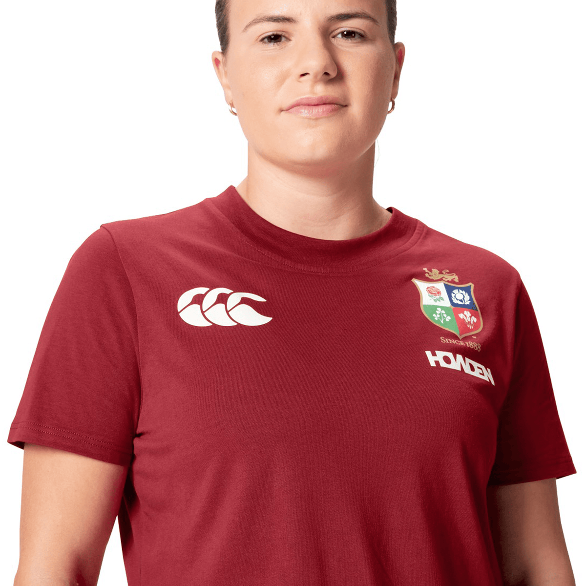 A rugby supporter proudly wears a Women's British &amp; Irish Lions 25 Cotton Jersey Tee by Canterbury, featuring logos on the front, embodying the spirit of the British &amp; Irish Lions.