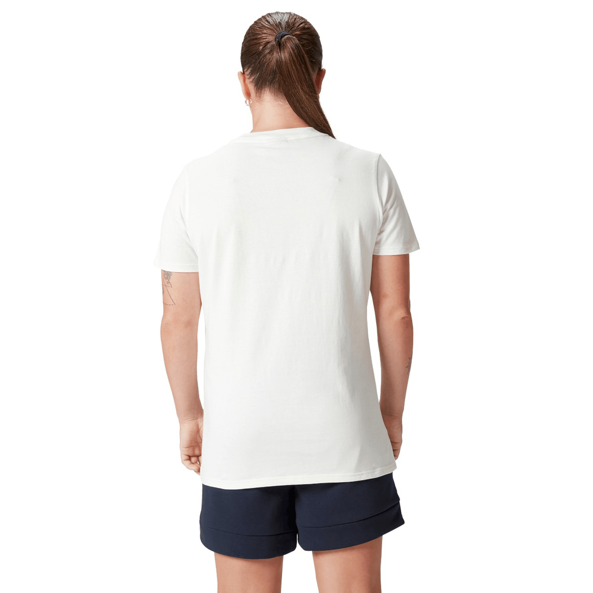 A person with a ponytail stands with their back to the camera, wearing a Women's British &amp; Irish Lions 25 Cotton Jersey Tee by Canterbury and dark shorts.