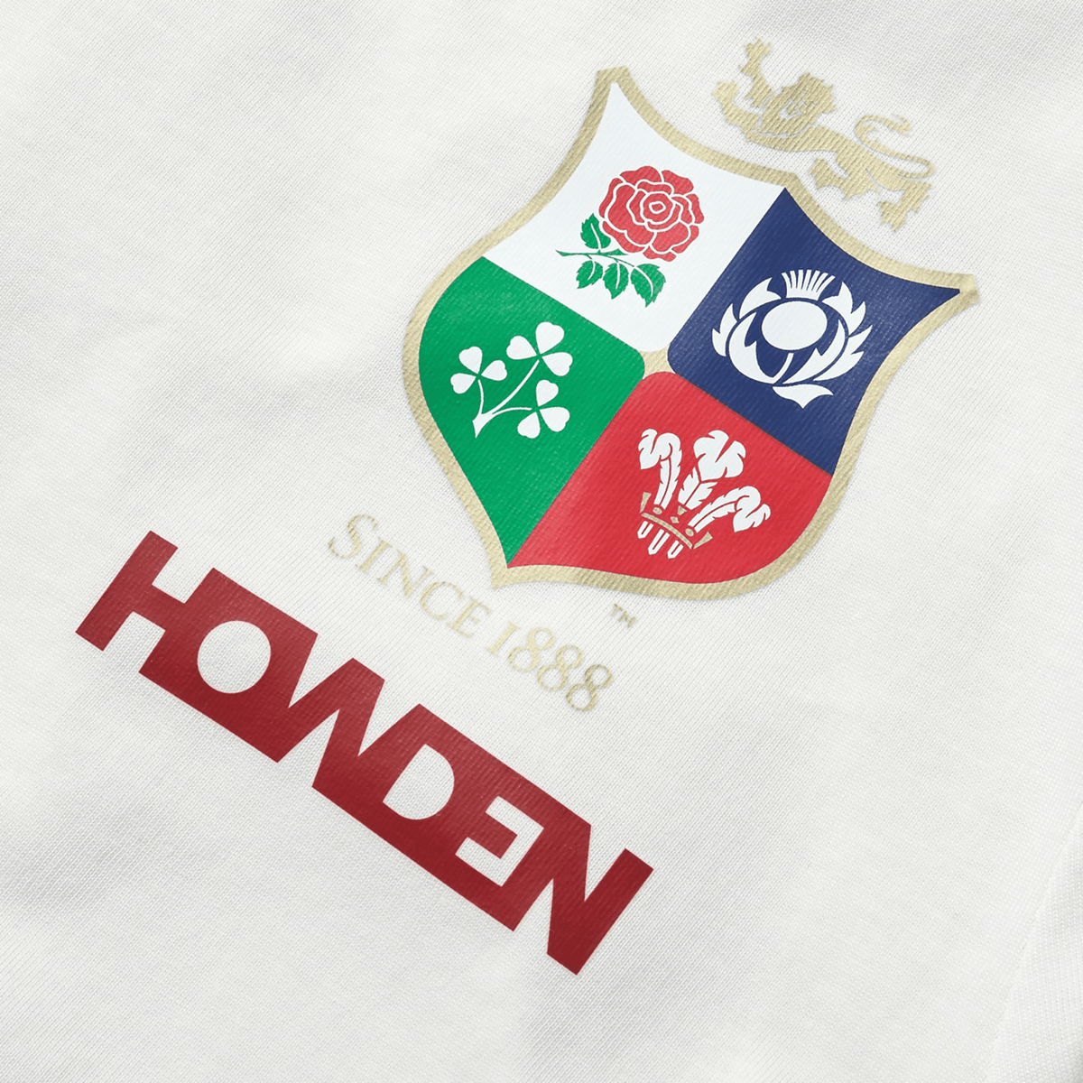 The Women's British &amp; Irish Lions 25 Cotton Jersey Tee by Canterbury showcases a logo with a shield featuring a lion, rose, shamrock, thistle, and feathers to celebrate the British &amp; Irish Lions. Above the logo is text reading "Since 1888" and "Howden" on a white background. This tee is perfect for any rugby supporter seeking timeless elegance.
