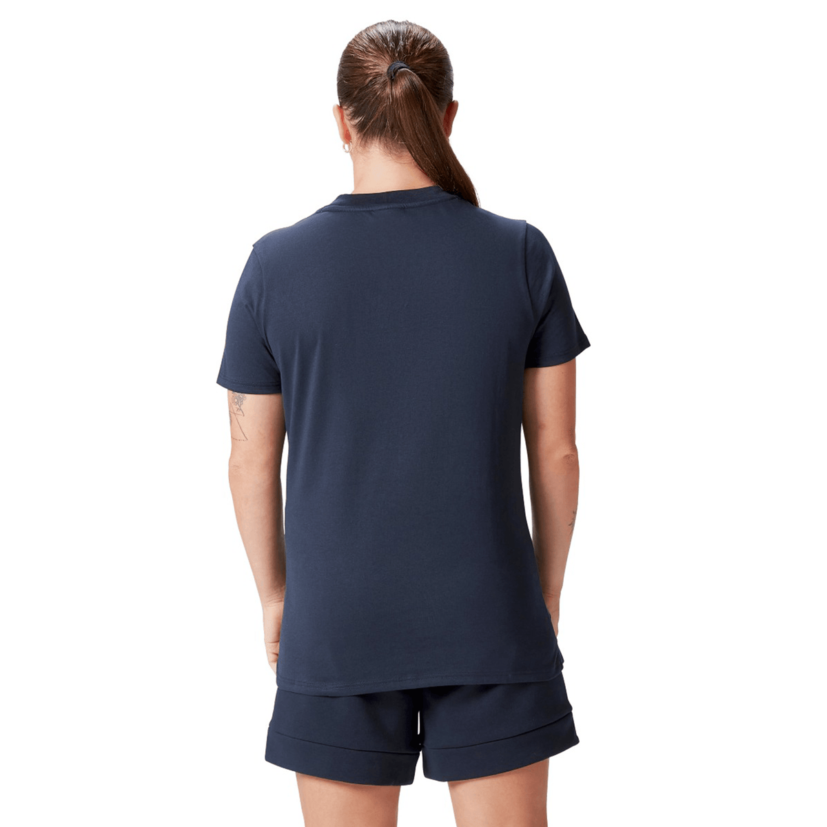 A person with a ponytail, wearing the Women's British &amp; Irish Lions 25 Cotton Jersey Tee by Canterbury and shorts, is seen from the back against a white background.