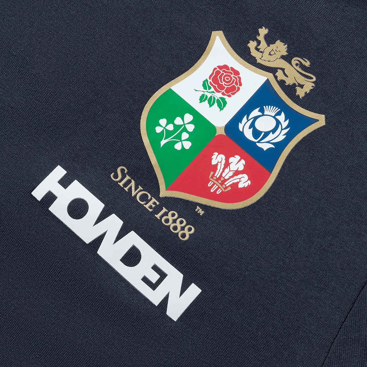 Close-up of a logo featuring a shield with a lion and four emblems: a rose, thistle, shamrock, and leek; the text reads "SINCE 1888" and "HONDEN" below. The British &amp; Irish Lions 2025 Women's Cotton Jersey Tee by Canterbury is perfect for the rugby supporter in your life.