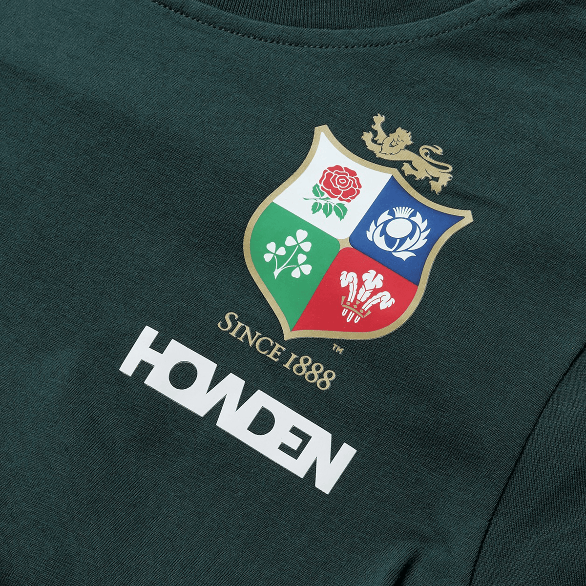 The Women's British &amp; Irish Lions 25 Cotton Jersey Tee by Canterbury is a dark green supporter shirt made from organic cotton, featuring a multicolored crest with a lion, rose, shamrock, thistle, and dragon. Below the crest are the words "Since 1888" and "HOWDEN," making it ideal for fans of the British &amp; Irish Lions.