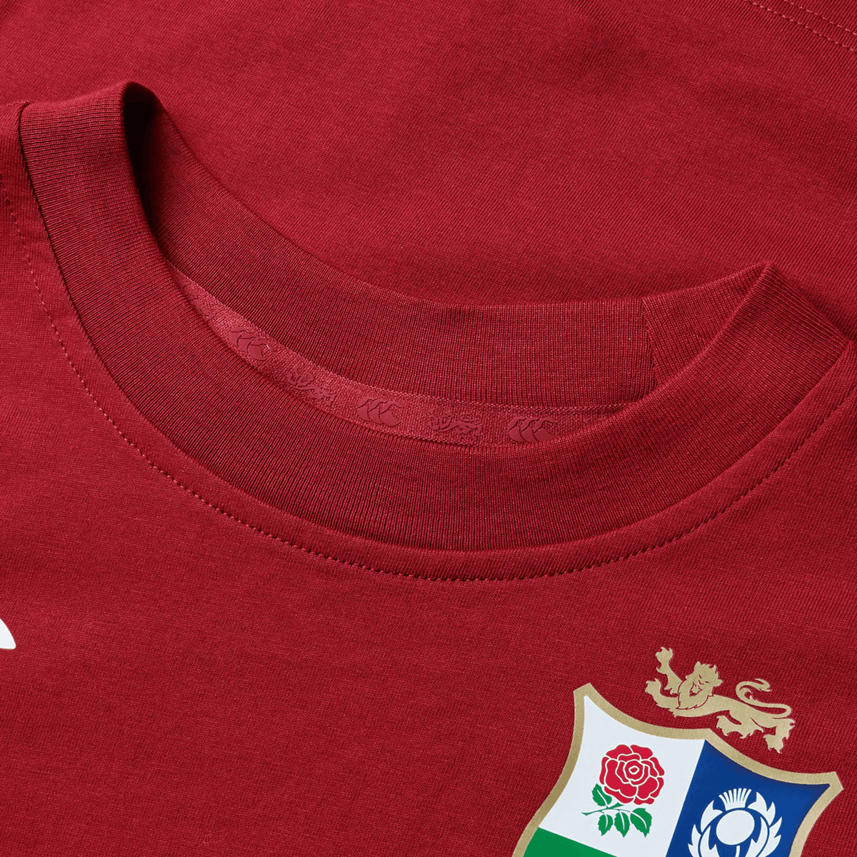 The Youth British &amp; Irish Lions 2025 Cotton Jersey Tee by Canterbury is a red sports jersey made from organic cotton, featuring a floral and animal crest on the chest—perfect for rugby supporters.