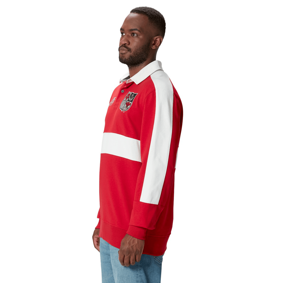 A man stands in profile wearing a red and white British &amp; Irish Lions 2025 Heritage Jersey by Canterbury, featuring an emblem on the chest.