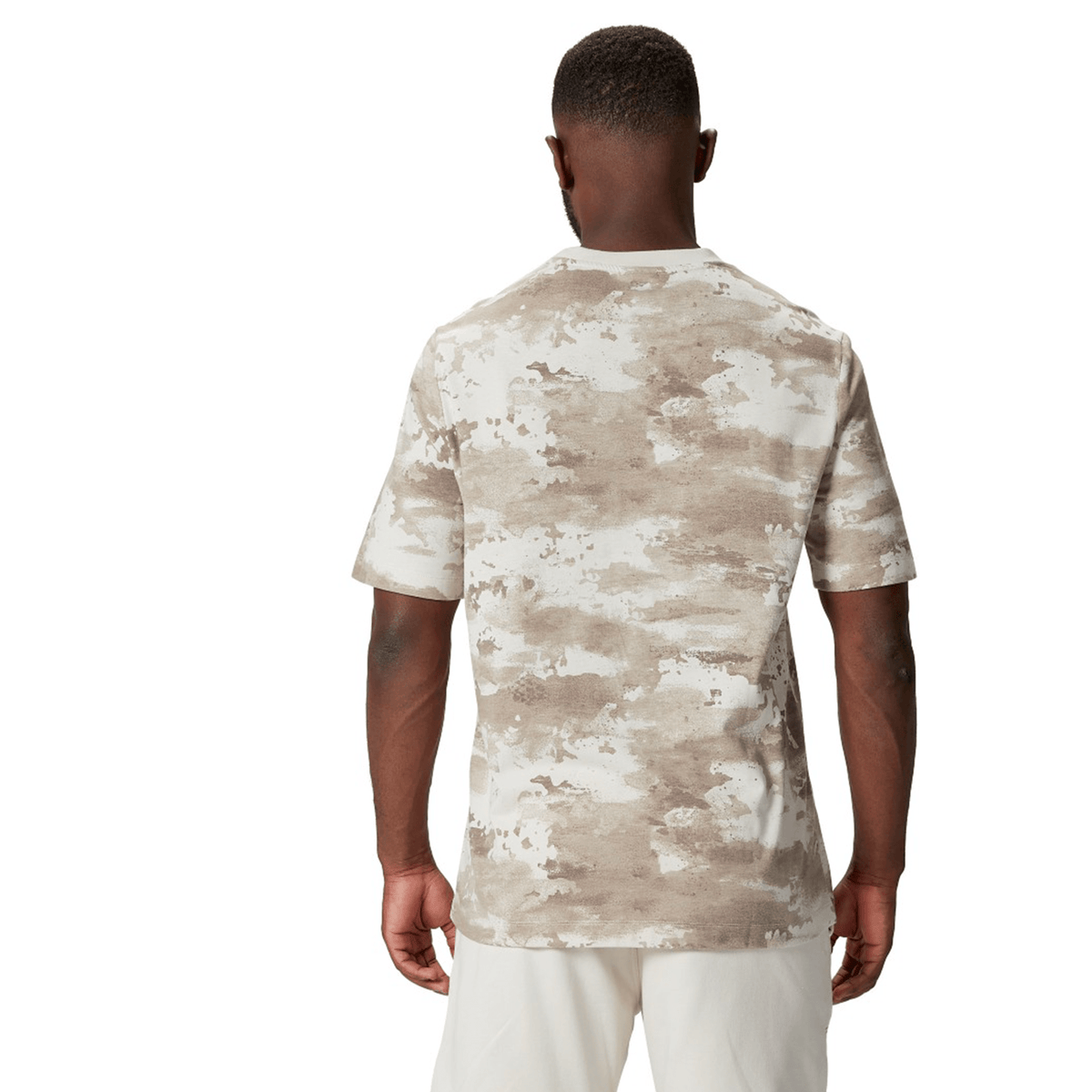 A person wearing the British &amp; Irish Lions 2025 Camo Tee by Canterbury in Desert Taupe and white pants is shown from the back.