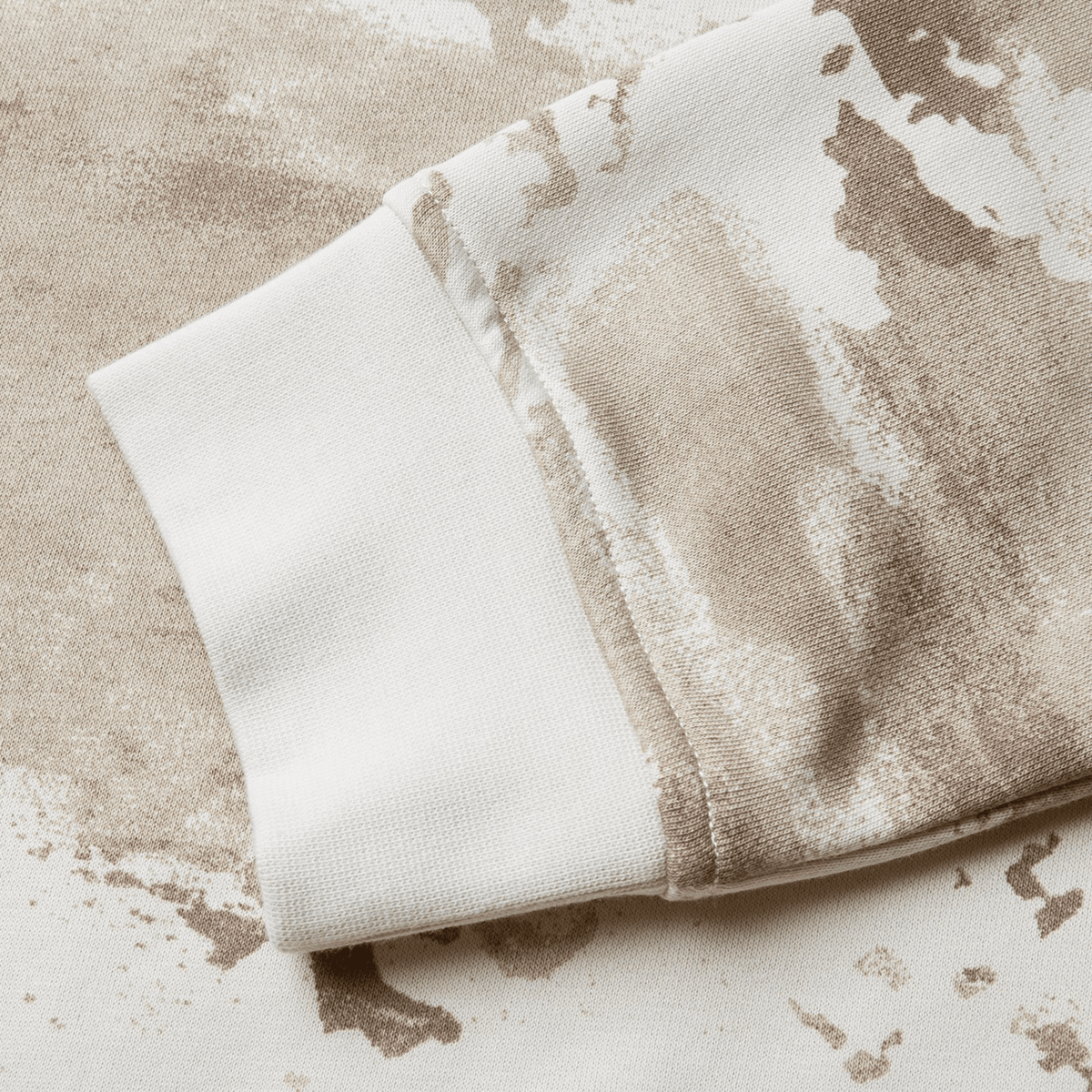 Close-up of a beige and white camouflage-patterned sleeve cuff on a fabric material from the British &amp; Irish Lions 25 Camo Crew Sweatshirt by Canterbury, inspired by the storied heritage of the British &amp; Irish Lions.