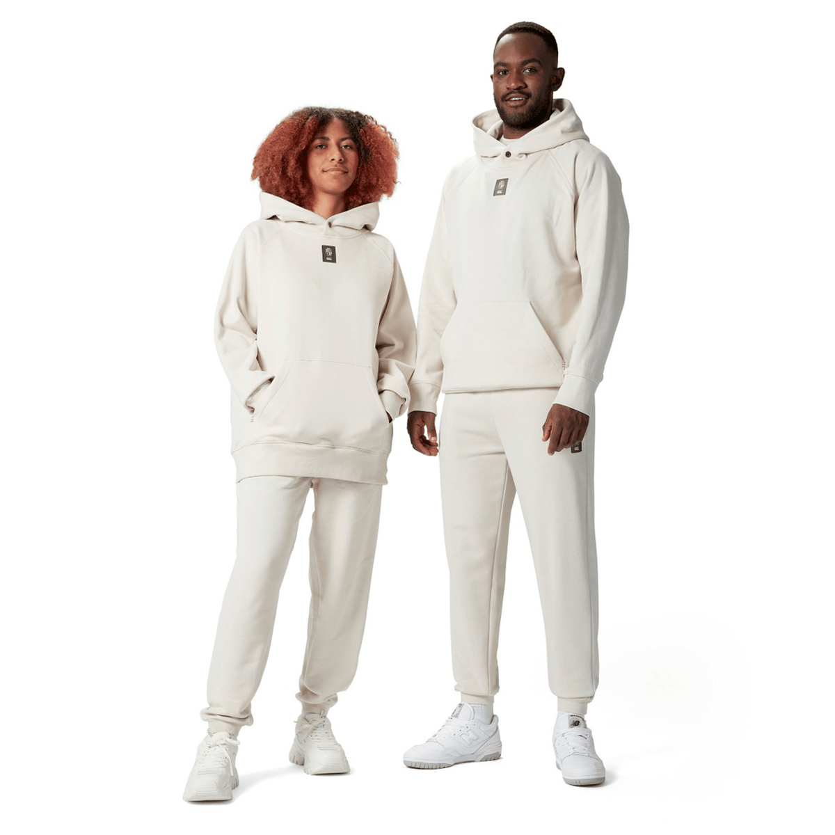 Two individuals wearing matching British &amp; Irish Lions 2025 Outback Fleece Hoodies by Canterbury and sweatpants stand side by side, both smiling.