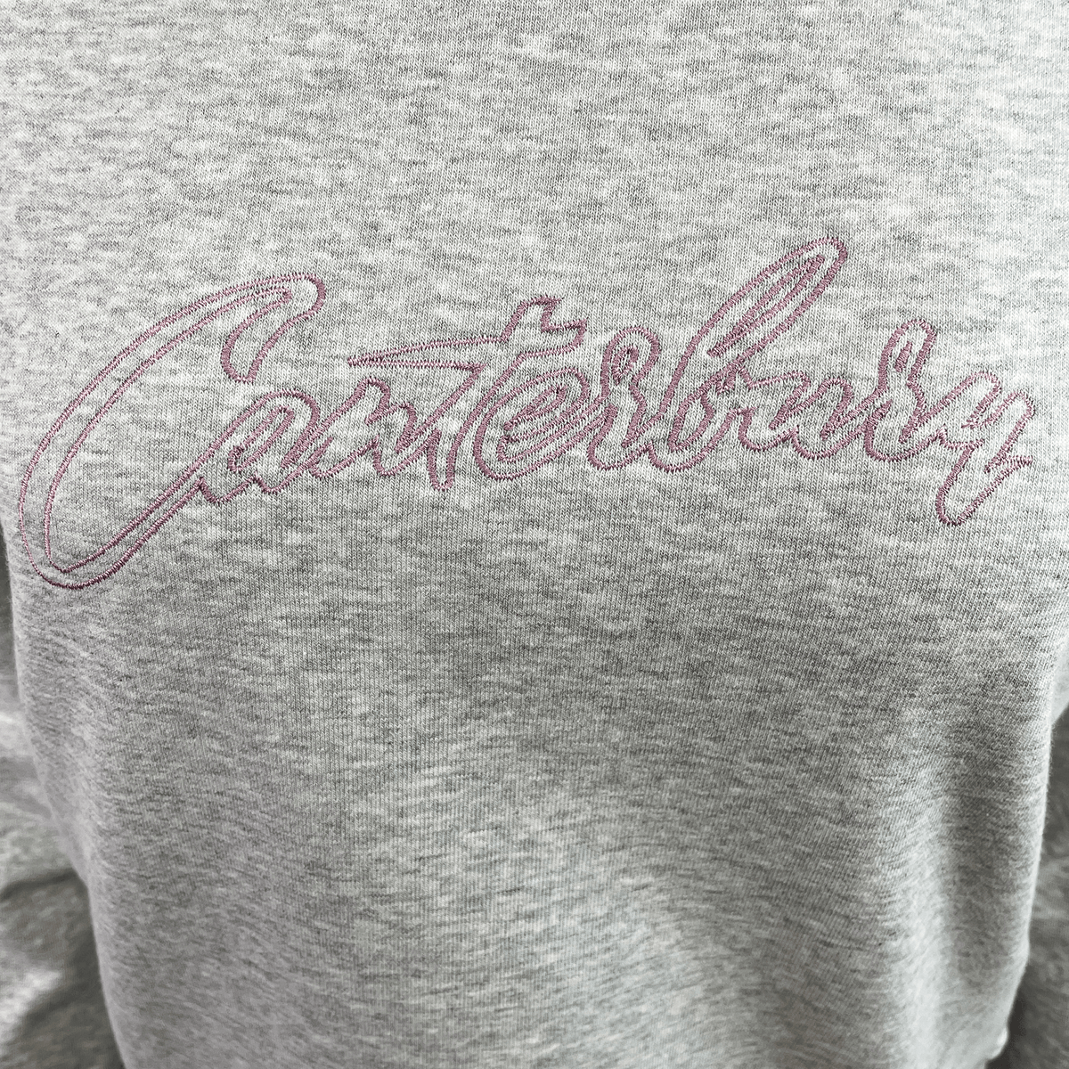 The Women&#39;s Canterbury Scene Set Crew Sweatshirt features &quot;Canterbury&quot; stitched in pink cursive on the front. This gray sweatshirt combines comfort and style with its relaxed fit, rib knit cuffs, and hem.