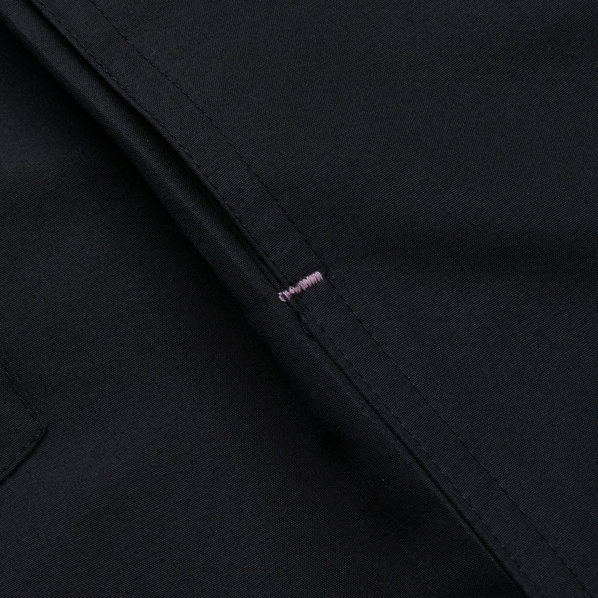 Close-up of the Canterbury Women&#39;s Uglies 5&quot; Tactic Short in black polyester, showcasing a vertical seam with a single pink stitch in the center.