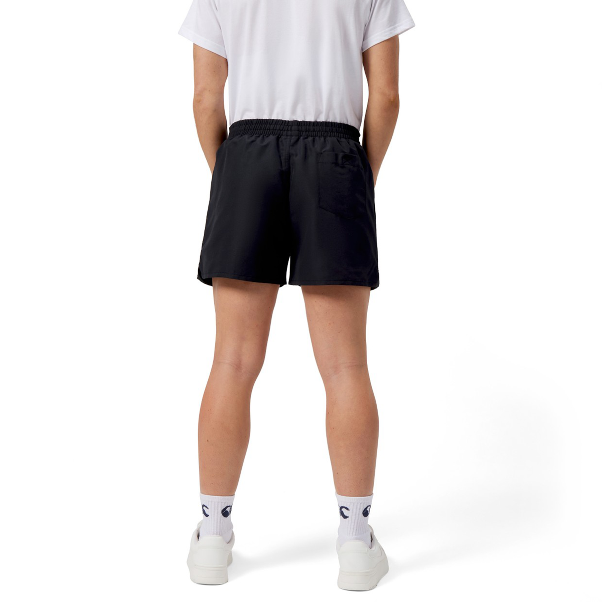 The individual is wearing a white t-shirt, Women&#39;s Canterbury Uglies 5&quot; Tactic Short in black polyester, and white logo-embossed socks, with Canterbury sneakers, set against a plain backdrop.