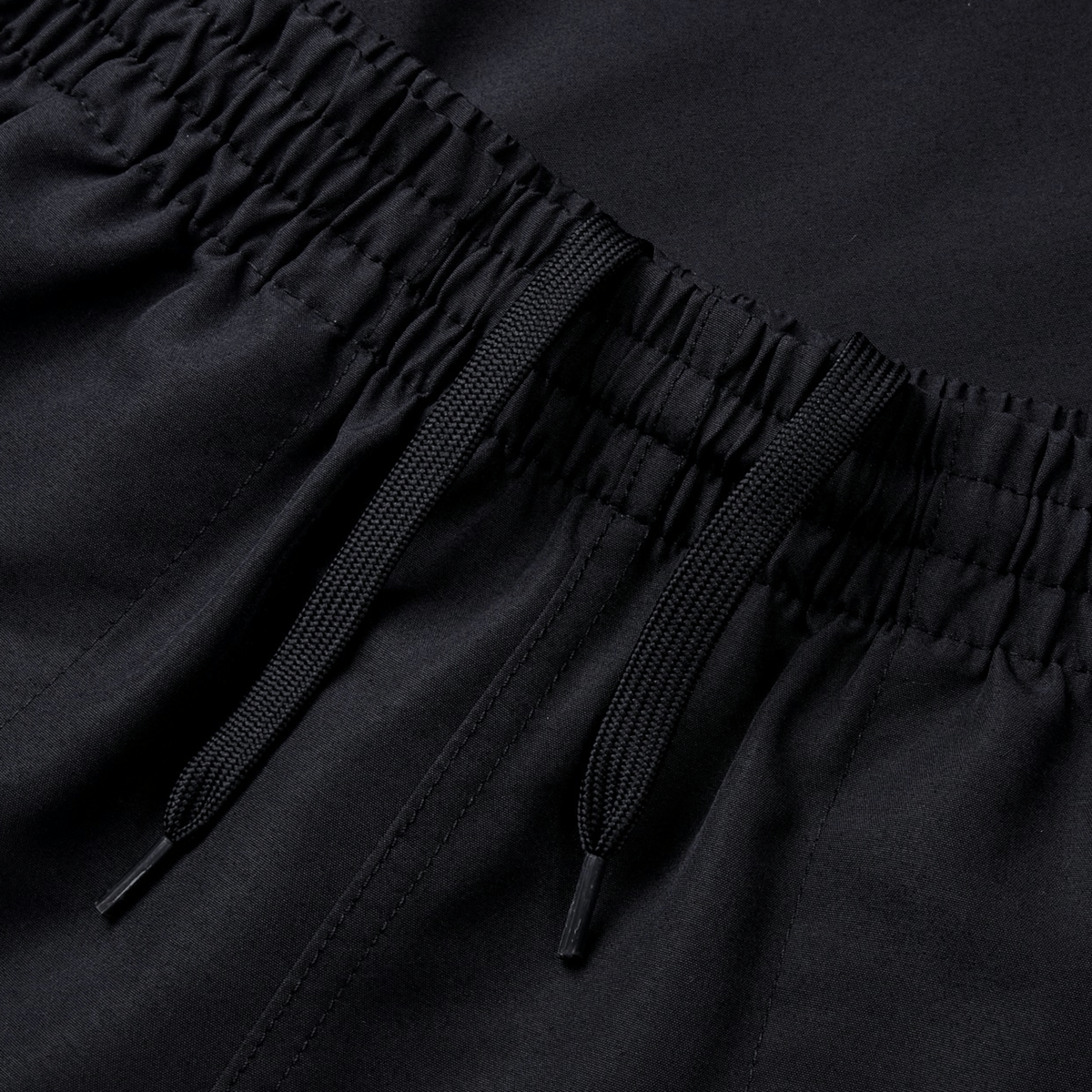 The Canterbury Fundamental 5" Panel Tactic Short features a close-up of black drawstring pants with an elastic waistband and two strings for tightening. These quick-drying shorts from Canterbury offer superior comfort, perfect for active days.
