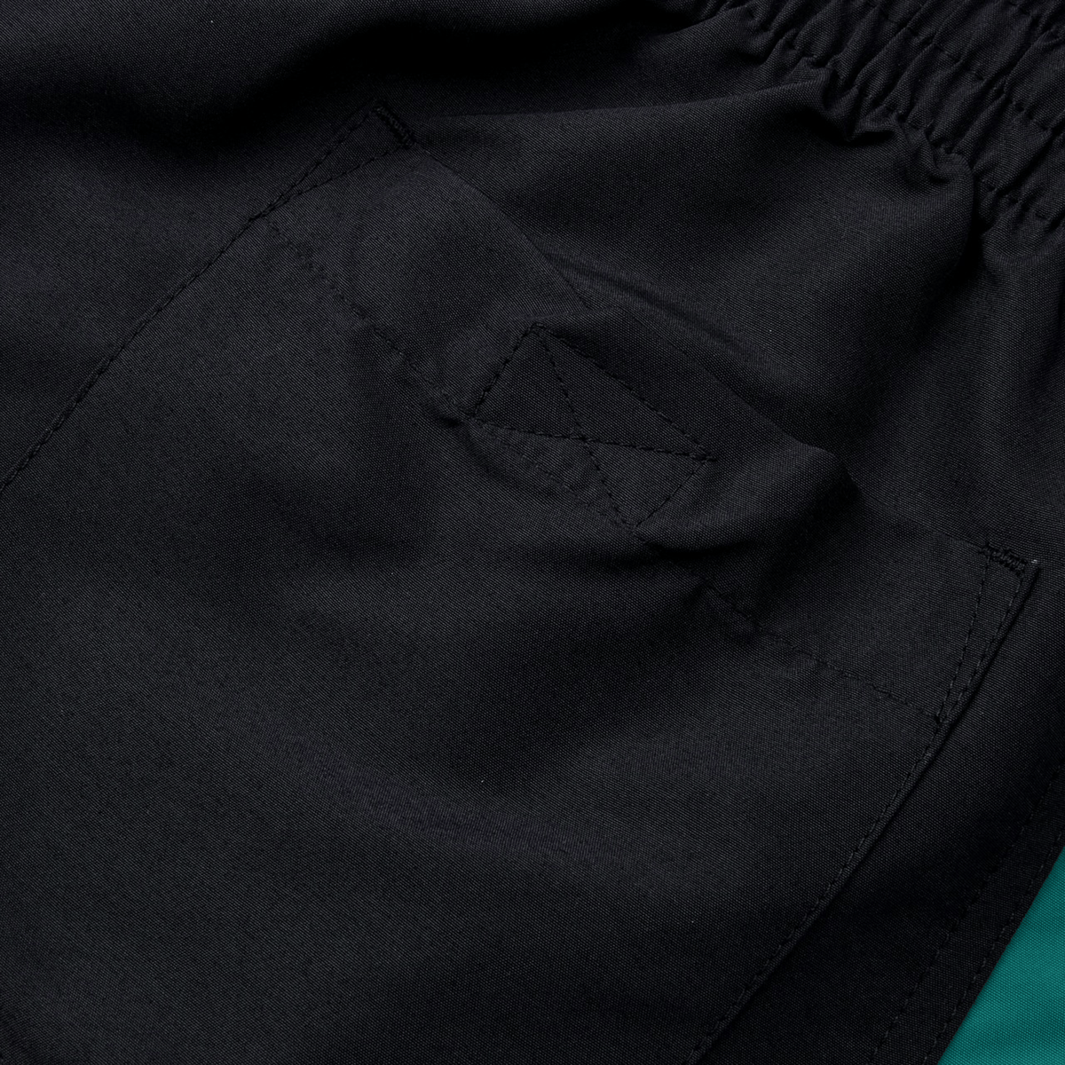Close-up of the back pocket on Canterbury Fundamental 5" Panel Tactic Shorts featuring an elastic waistband. The smooth, slightly reflective material enhances performance with moisture-wicking and quick-drying capabilities.