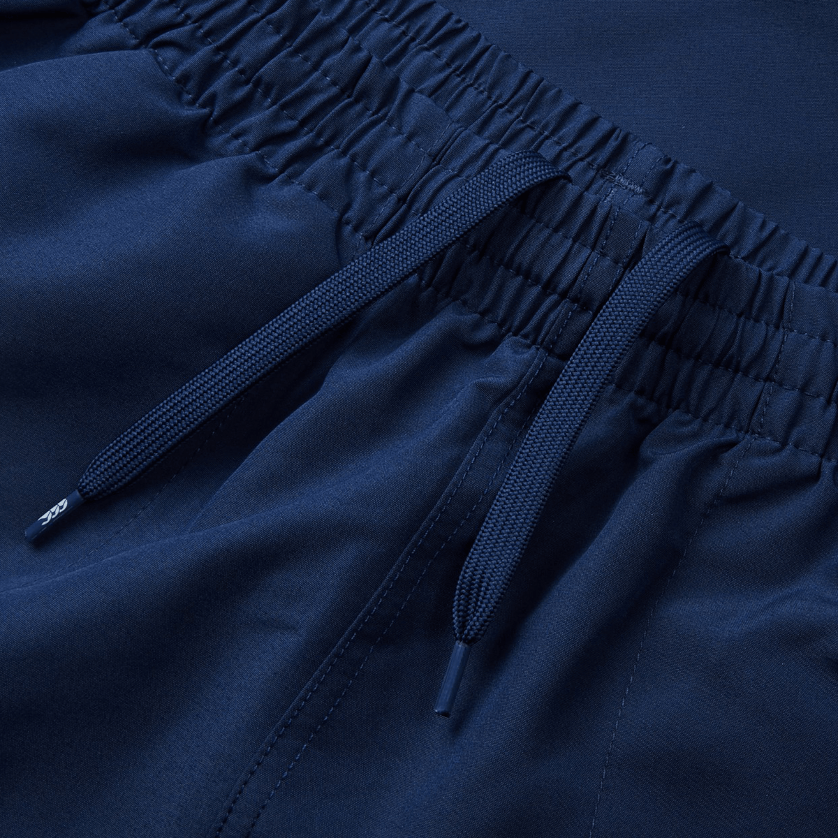 Close-up of navy blue fabric pants featuring an elastic waistband and drawstrings, combining the sleek comfort reminiscent of Canterbury Fundamental 5" Panel Tactic Shorts with the convenience of quick-drying material.