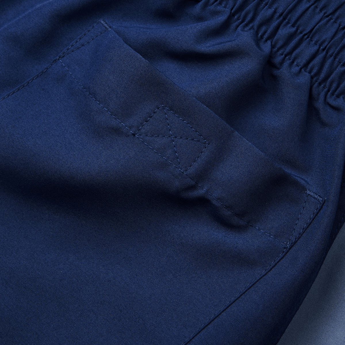 Close-up of the back pocket of a blue Canterbury Fundamental 5" Panel Tactic Short, highlighting detailed stitching and an elastic waistband. These Canterbury shorts are moisture-wicking, ensuring comfort and quick drying.