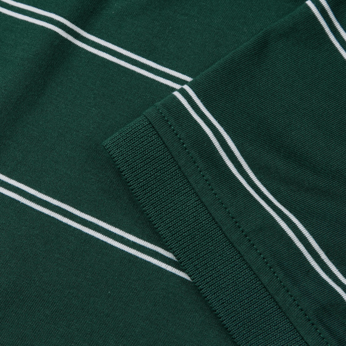 Close-up of Canterbury Fundamental Yarn-Dye Stripe Polo's green fabric with white stripes and a ribbed cuff sleeve, reminiscent of classic Canterbury polos.