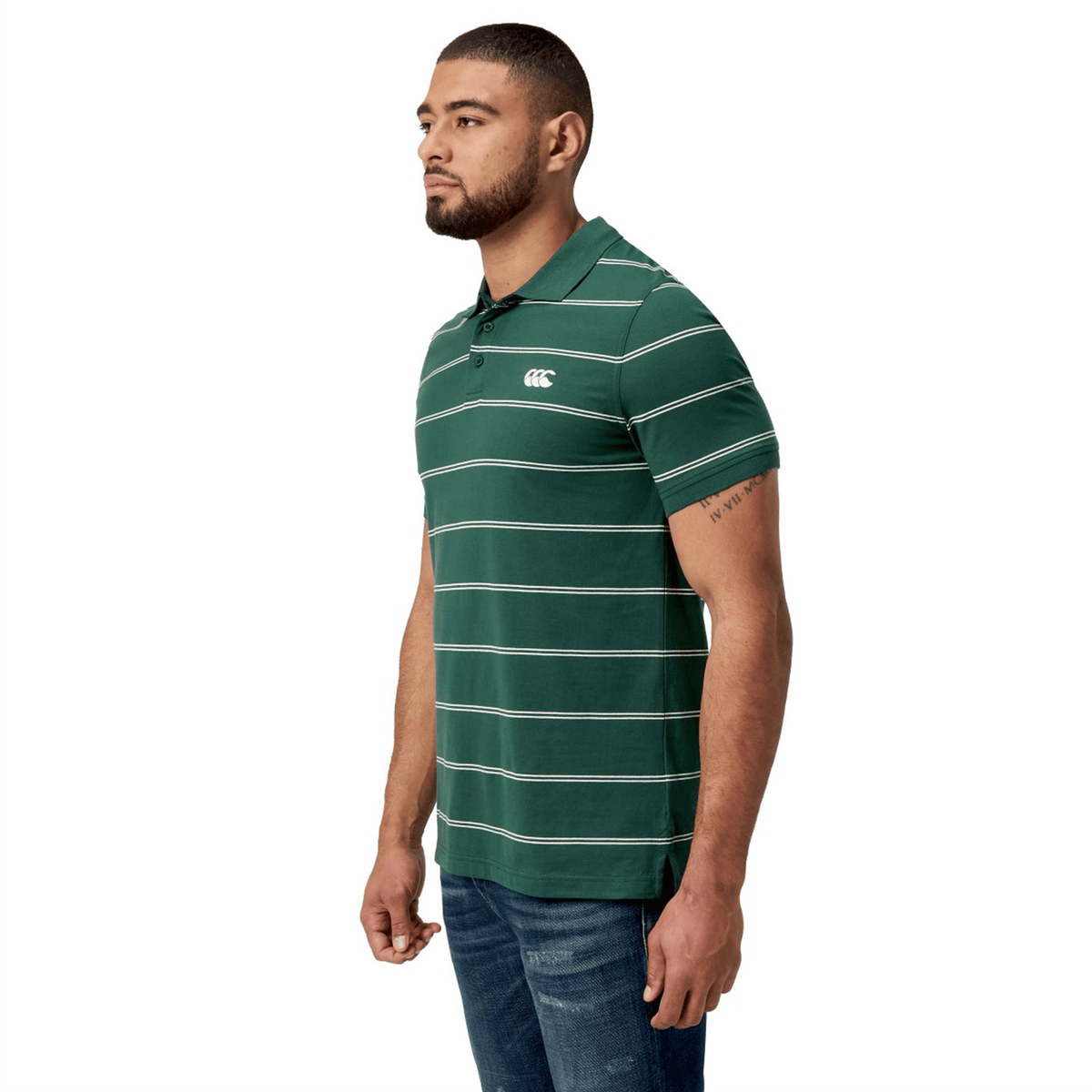 A man in profile wears the Canterbury Fundamental Yarn-Dye Stripe Polo and blue jeans against a white background.