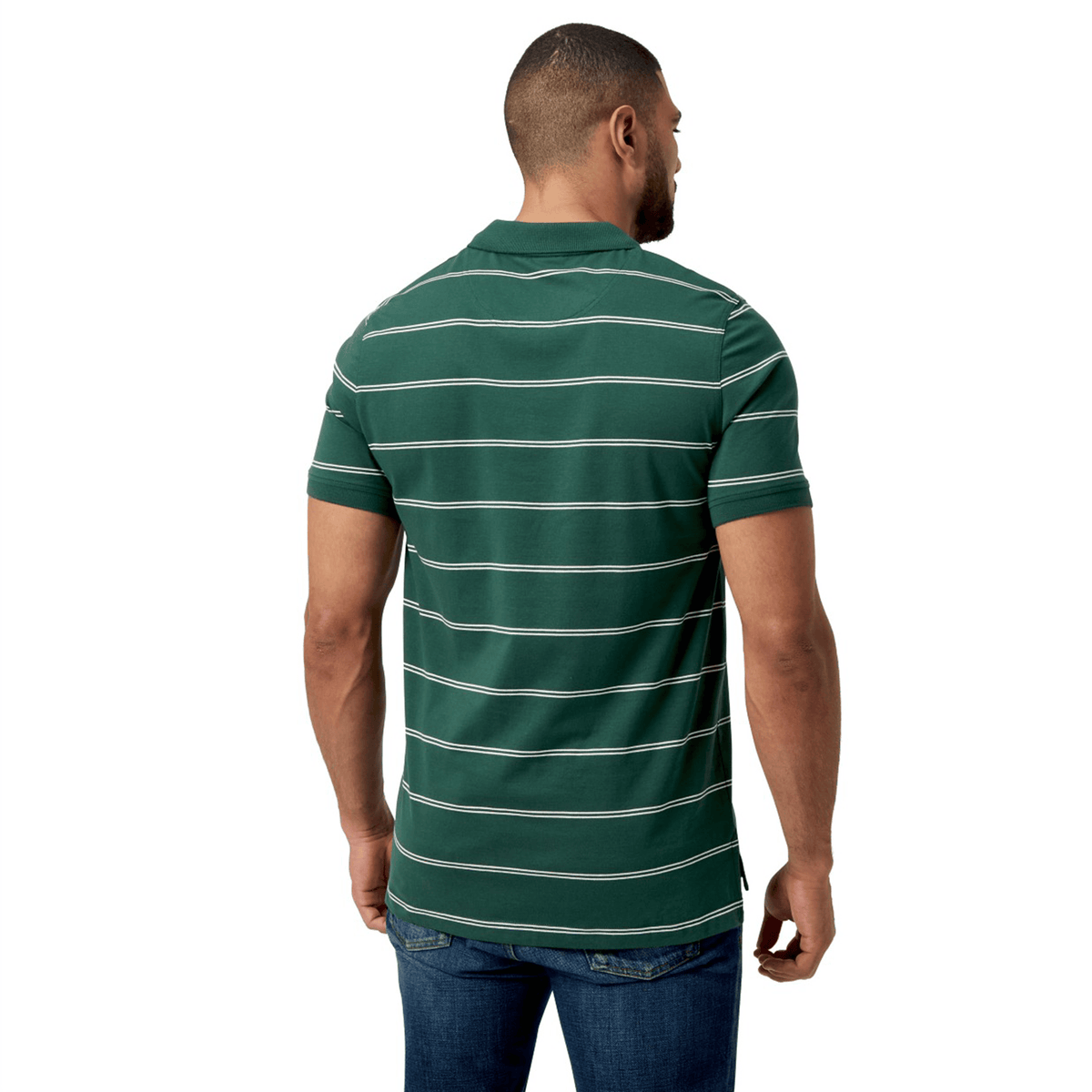 The person faces away from the camera, wearing a Canterbury Fundamental Yarn-Dye Stripe Polo in green and white, paired with classic blue jeans.