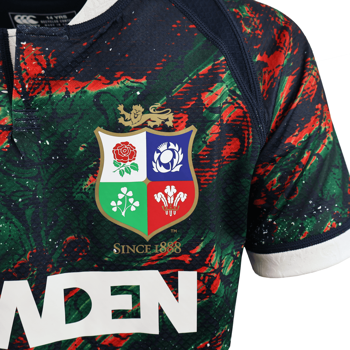 The Youth British &amp; Irish Lions 2025 Warm Up Jersey by Canterbury features the iconic emblem with a vibrant red floral and green clover design. Made from moisture-wicking fabric, it ensures comfort for all wearers.