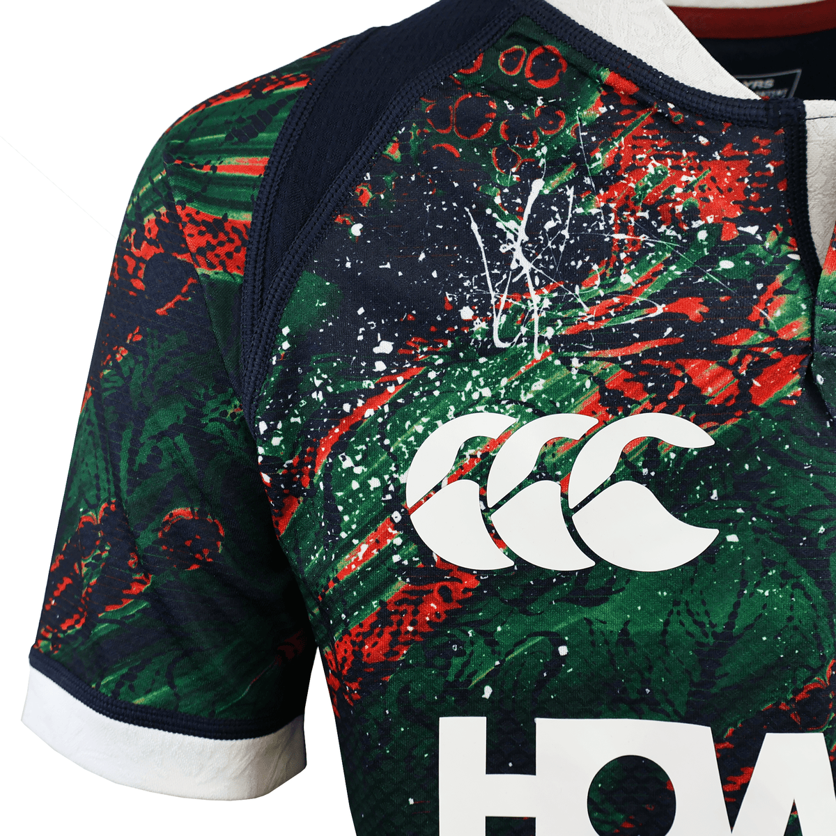 Close-up of the Youth British &amp; Irish Lions 2025 Warm Up Jersey by Canterbury featuring a colorful abstract design in red, green, and black, with a white Canterbury logo on the chest. Made from moisture-wicking fabric for comfort both on and off the field.