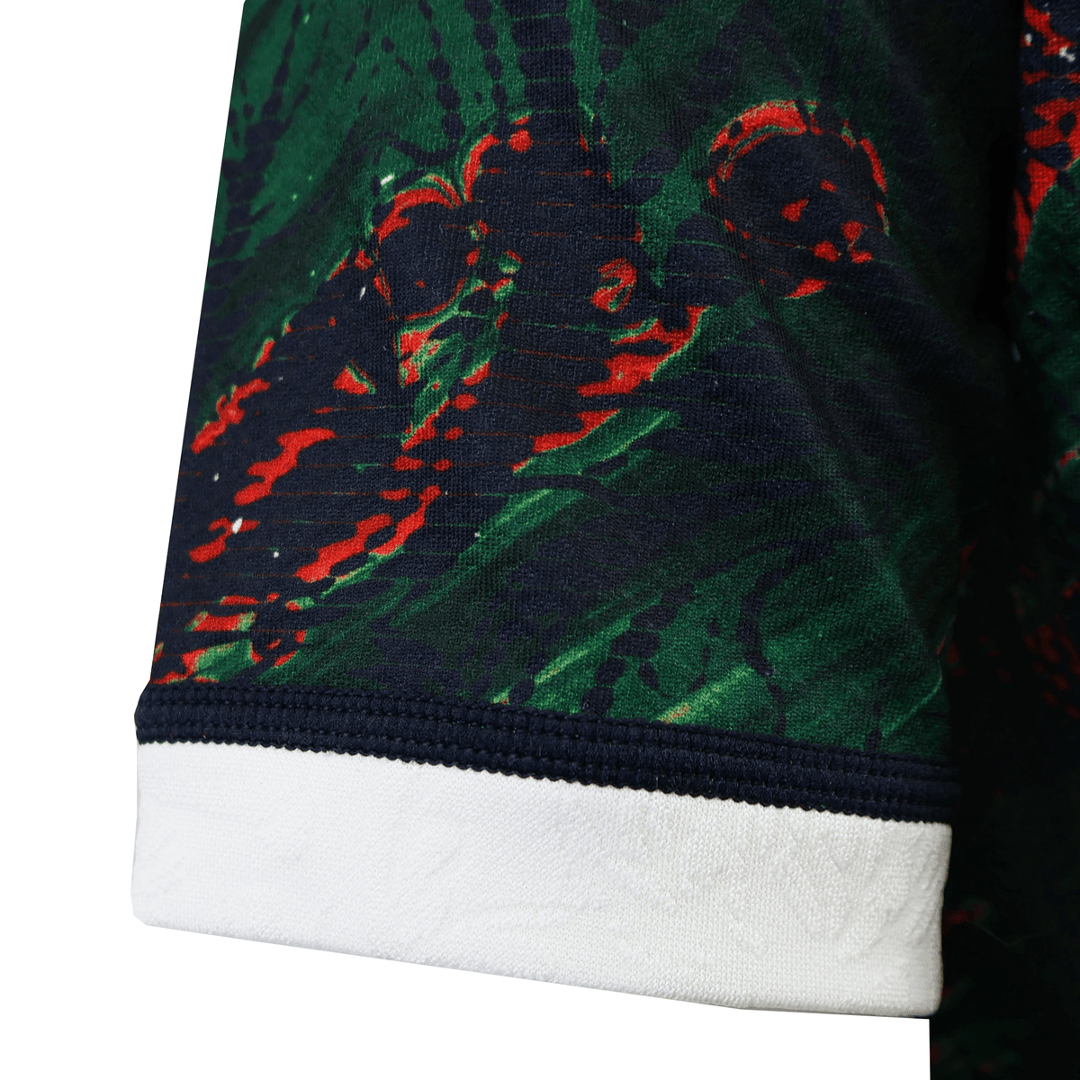 Close-up of a British &amp; Irish Lions 2025 Warm Up Jersey sleeve, in dark green and red patterns with a white cuff, made from moisture-wicking fabric by Canterbury.