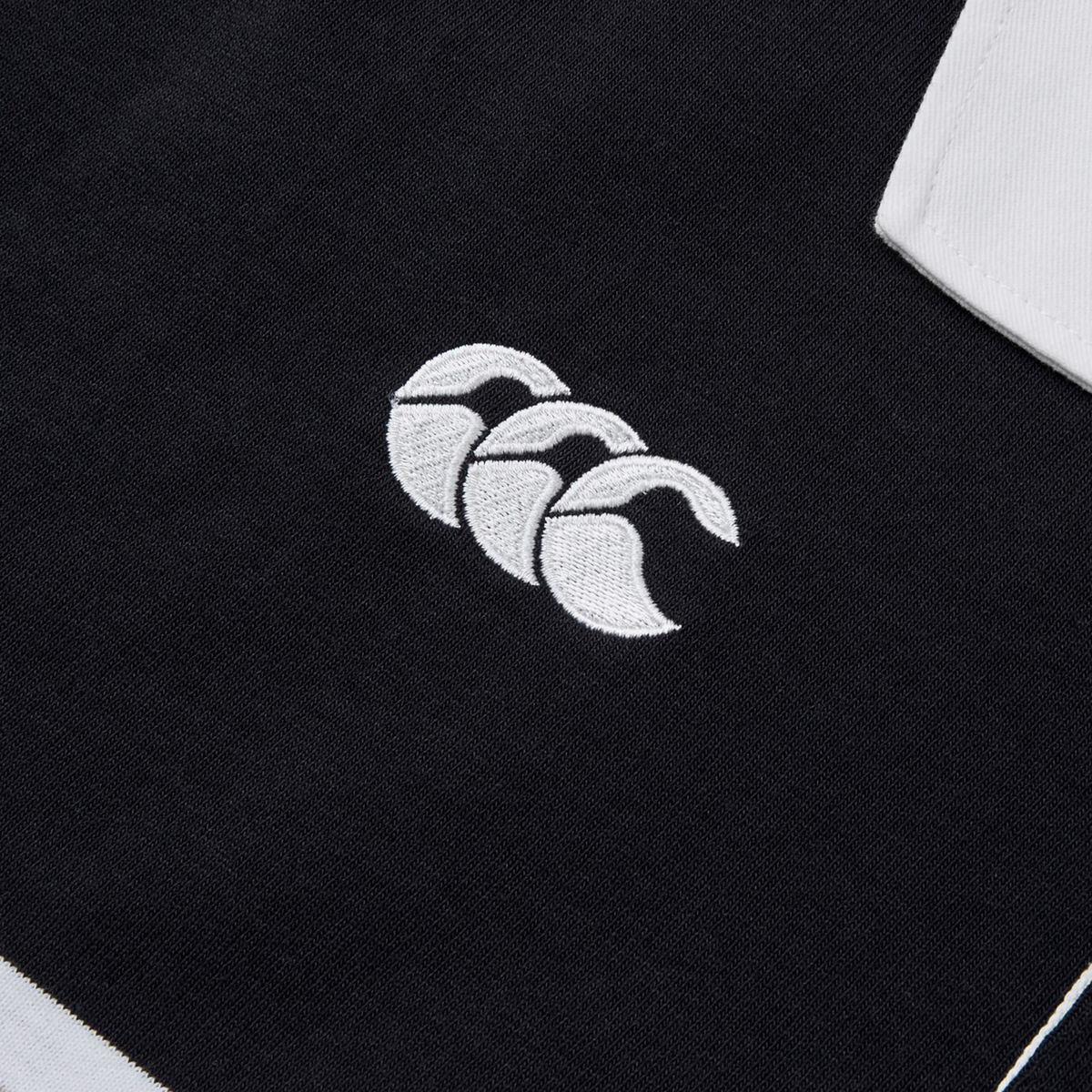 Close-up of a black fabric featuring the white, stylized triple wave logo, reminiscent of the Canterbury Yarn Dye Short Sleeve Rugby Jersey design.